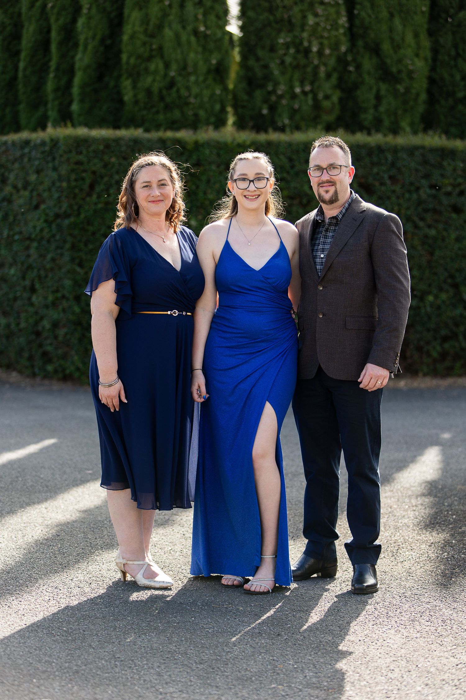 Family gathering in formal wear posing on paved outdoor area.