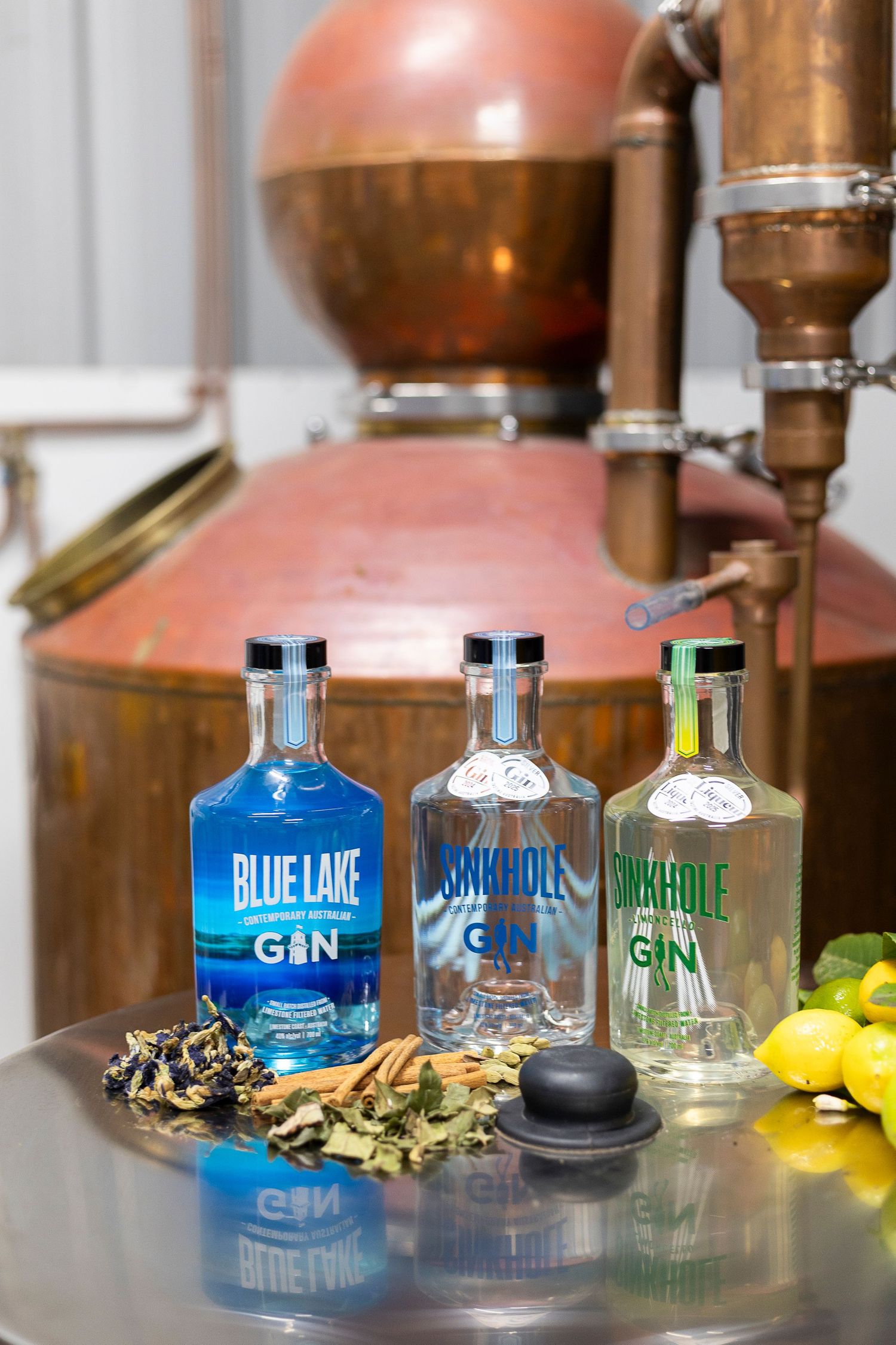 Display of Blue Lake gin bottles with copper distillery equipment in the background.