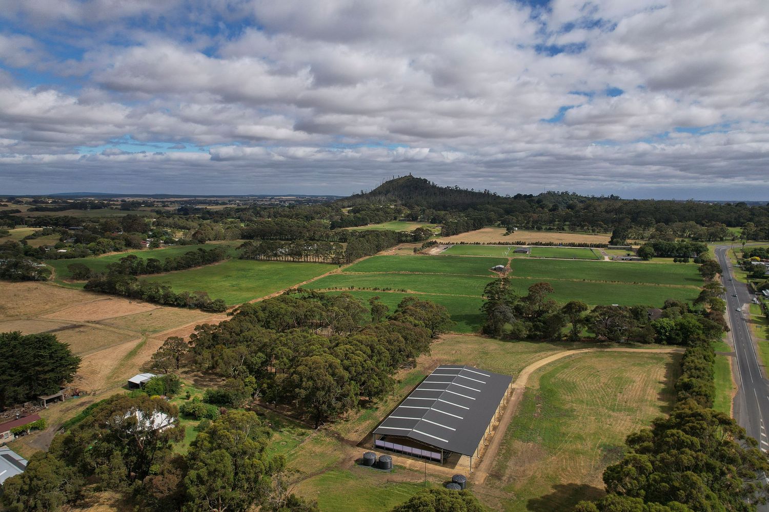 Aerial panorama of rural property with equestrian facilities and green pastures.