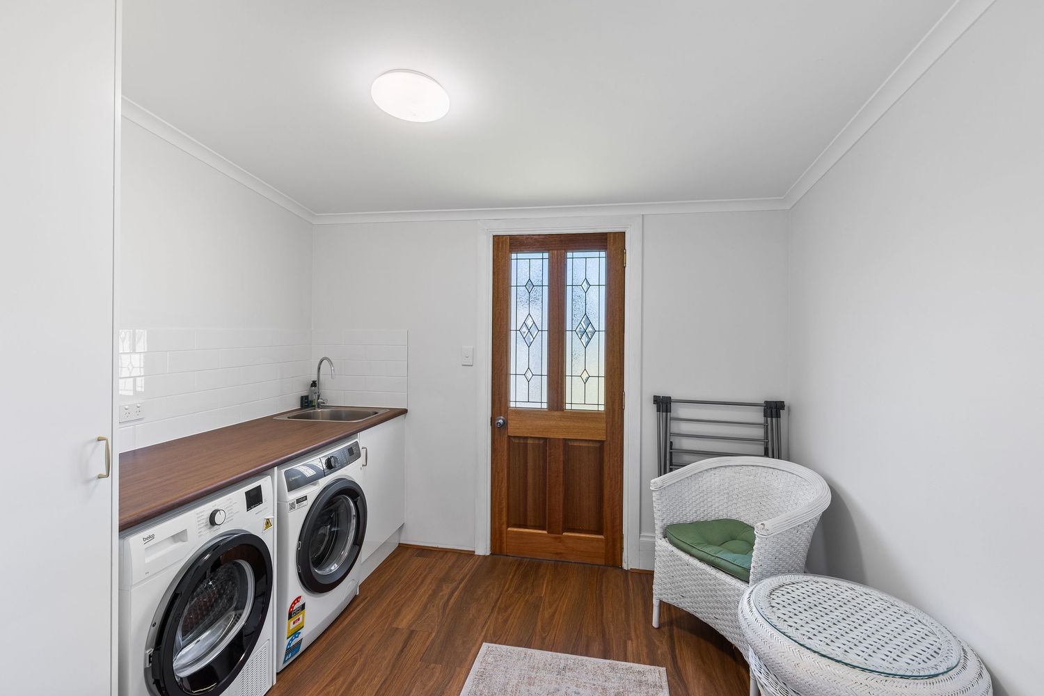 Laundry room with modern washer and dryer, wooden door, and ample storage space.