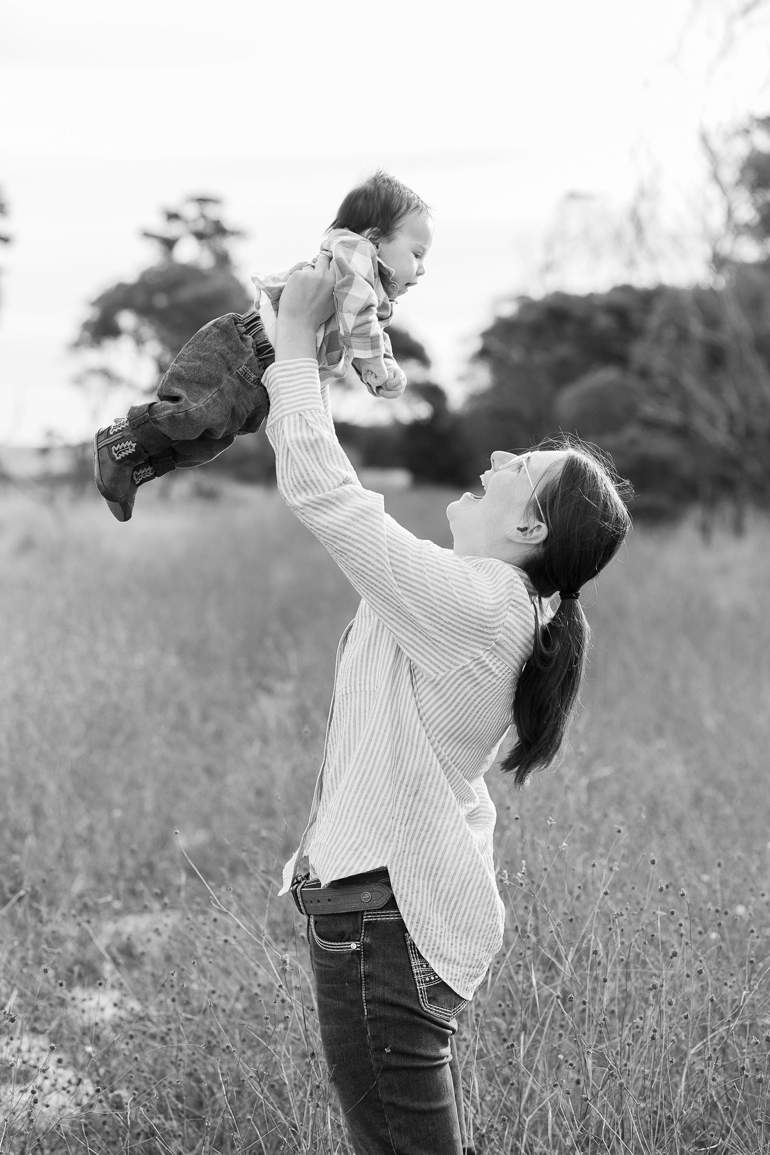 A joyful moment in a field as a parent lifts a child into the air.