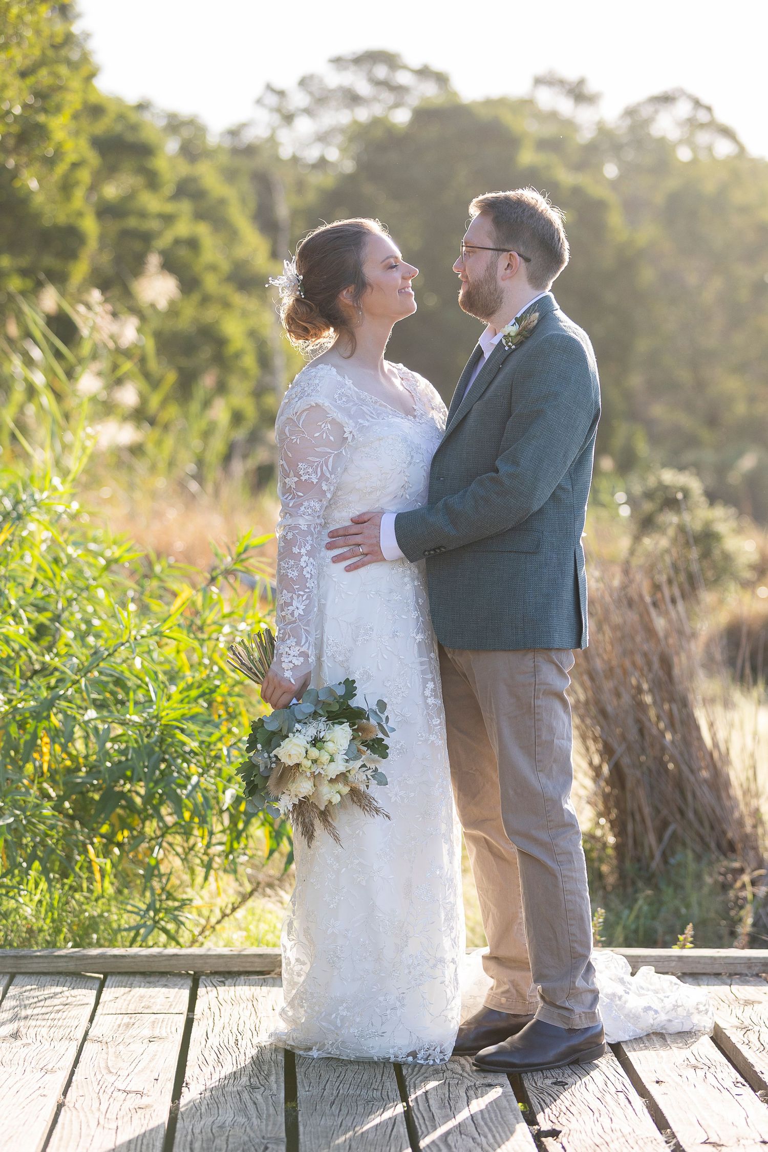 A romantic outdoor wedding portrait session in golden sunlight among tall grasses.