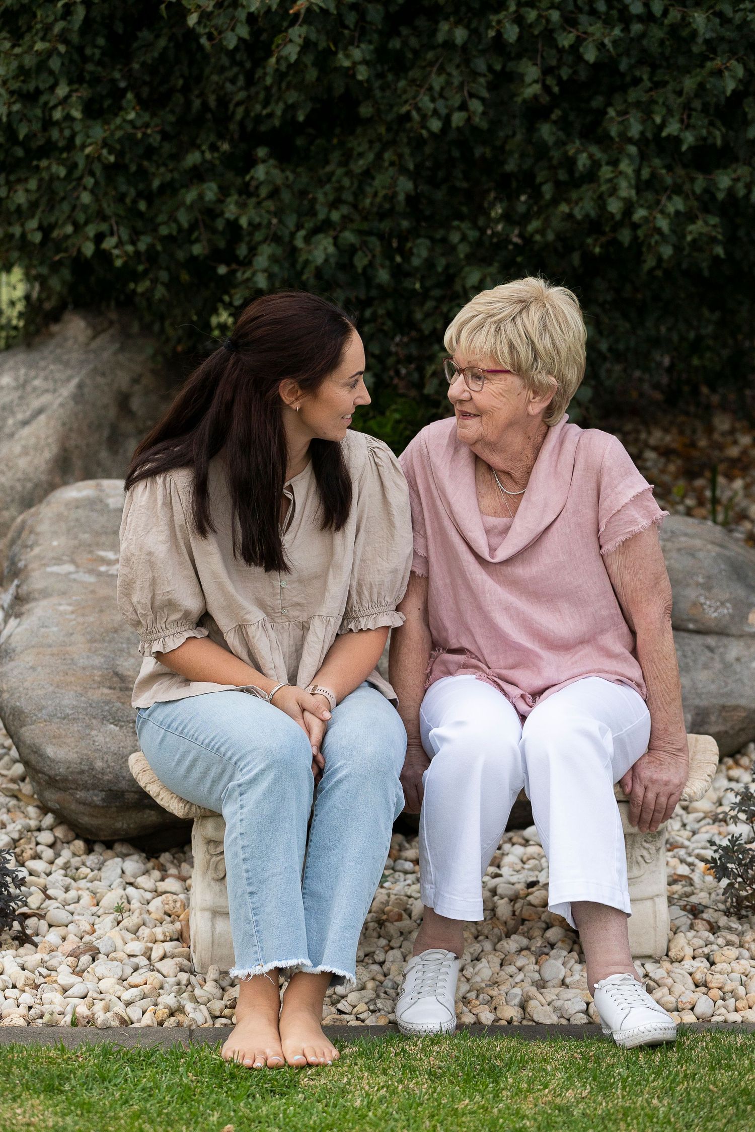 Two people sitting on rock wall having intimate conversation in garden setting.