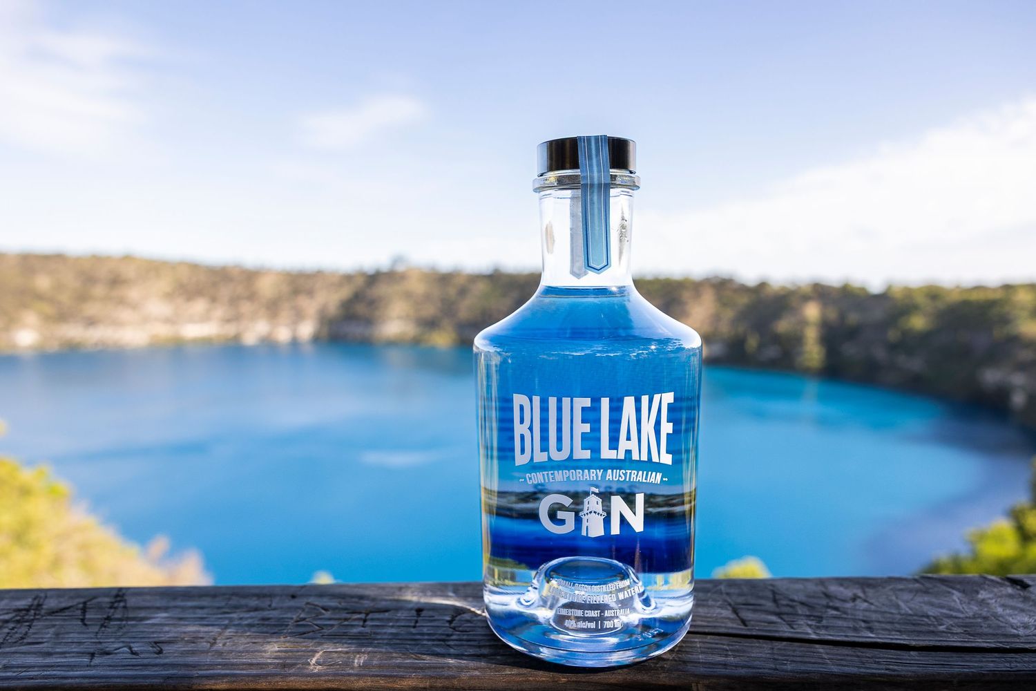 Blue Lake gin bottle displayed on rocky ledge overlooking bright blue lake