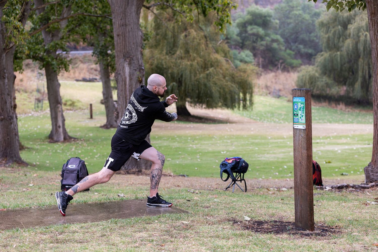 People exercising at outdoor fitness stations among trees in a park setting.