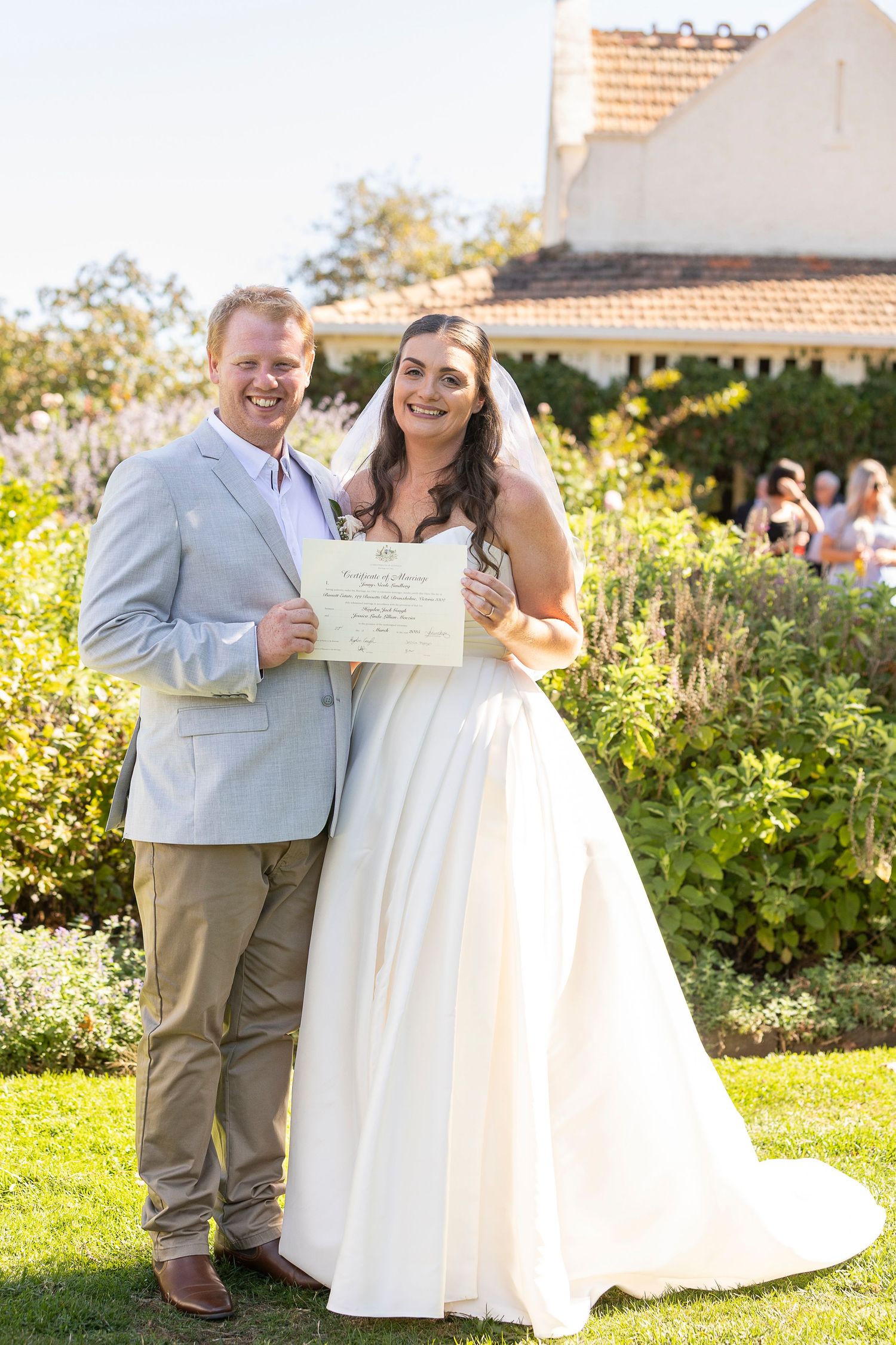 A joyful wedding celebration in a sunny garden setting with white dress and light gray suit.