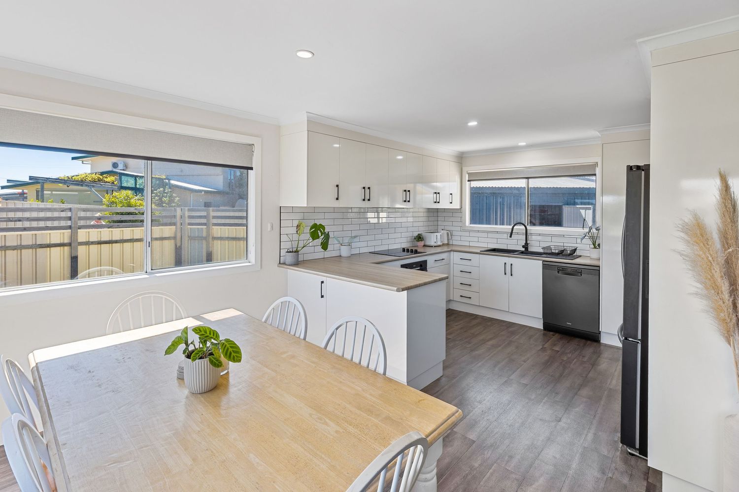 Bright open concept kitchen and dining area with wood floors and white cabinetry.