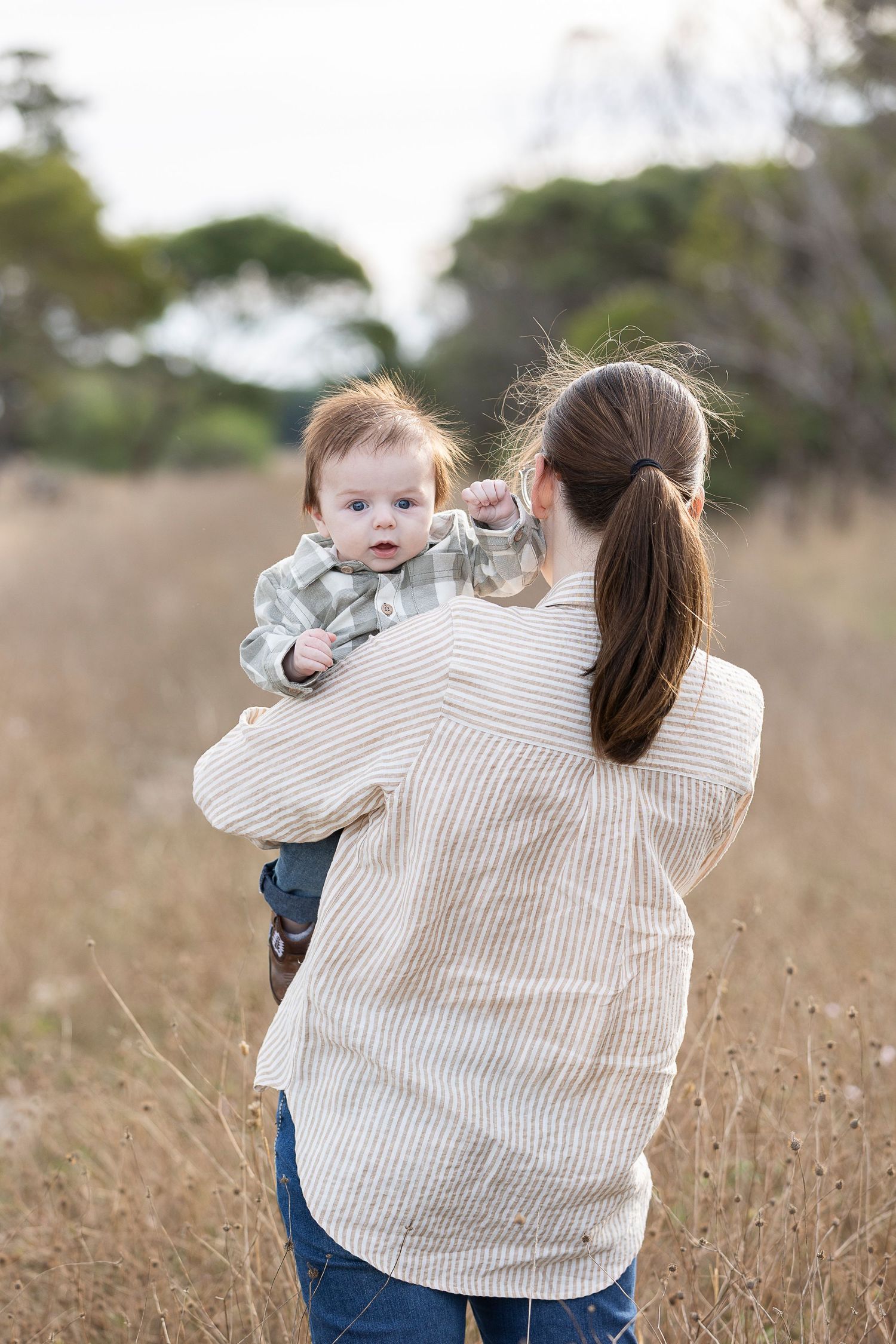 A parent and child sharing a tender moment in a golden field at sunset.