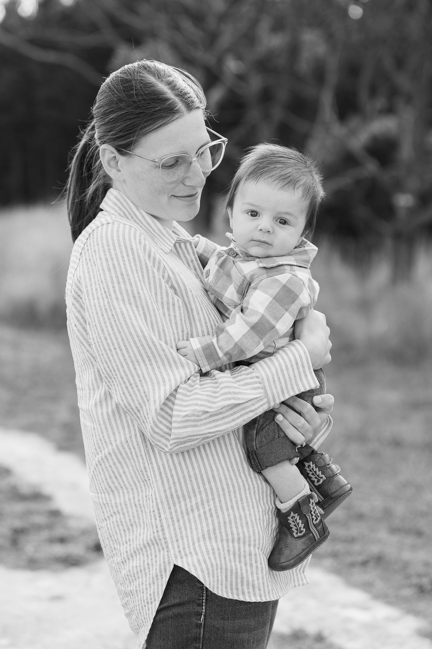 Black and white photos showing gentle interaction between adult and infant outdoors.