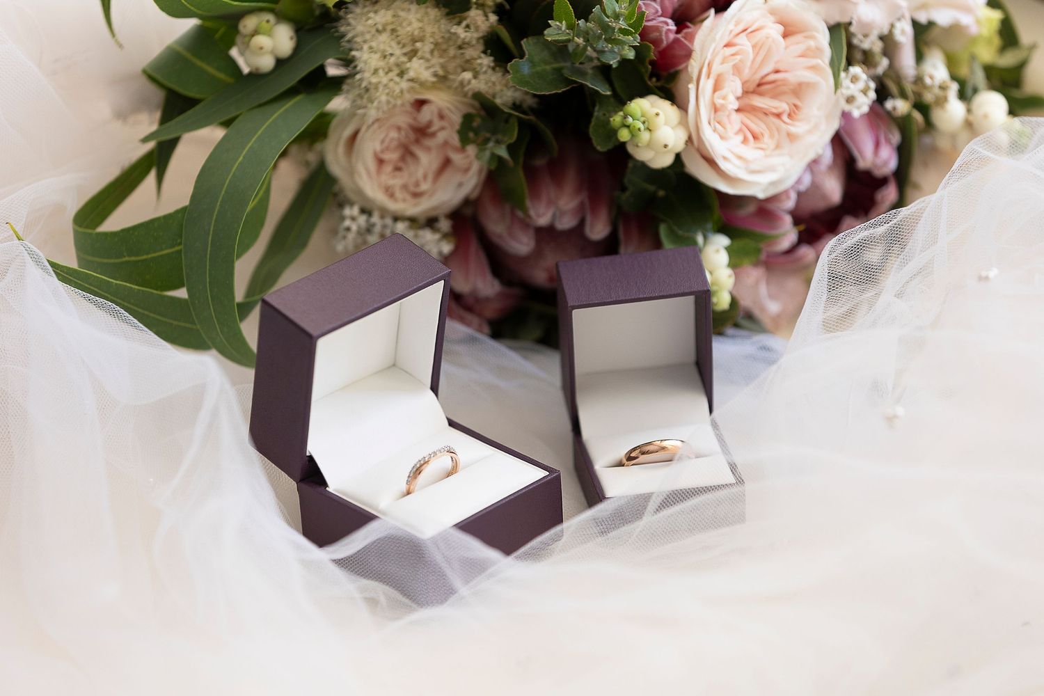 Wedding floral arrangement with pink garden roses and delicate white flowers alongside brown gift boxes.