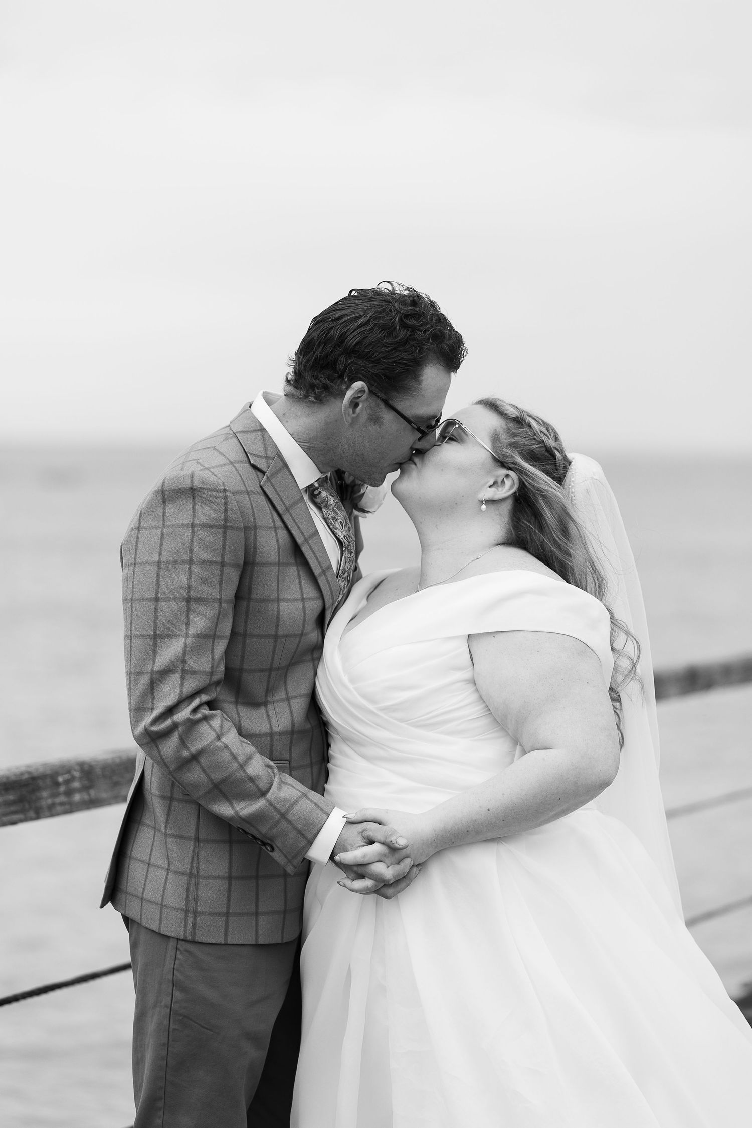 Wedding couple embraces on a cloudy day in black and white.