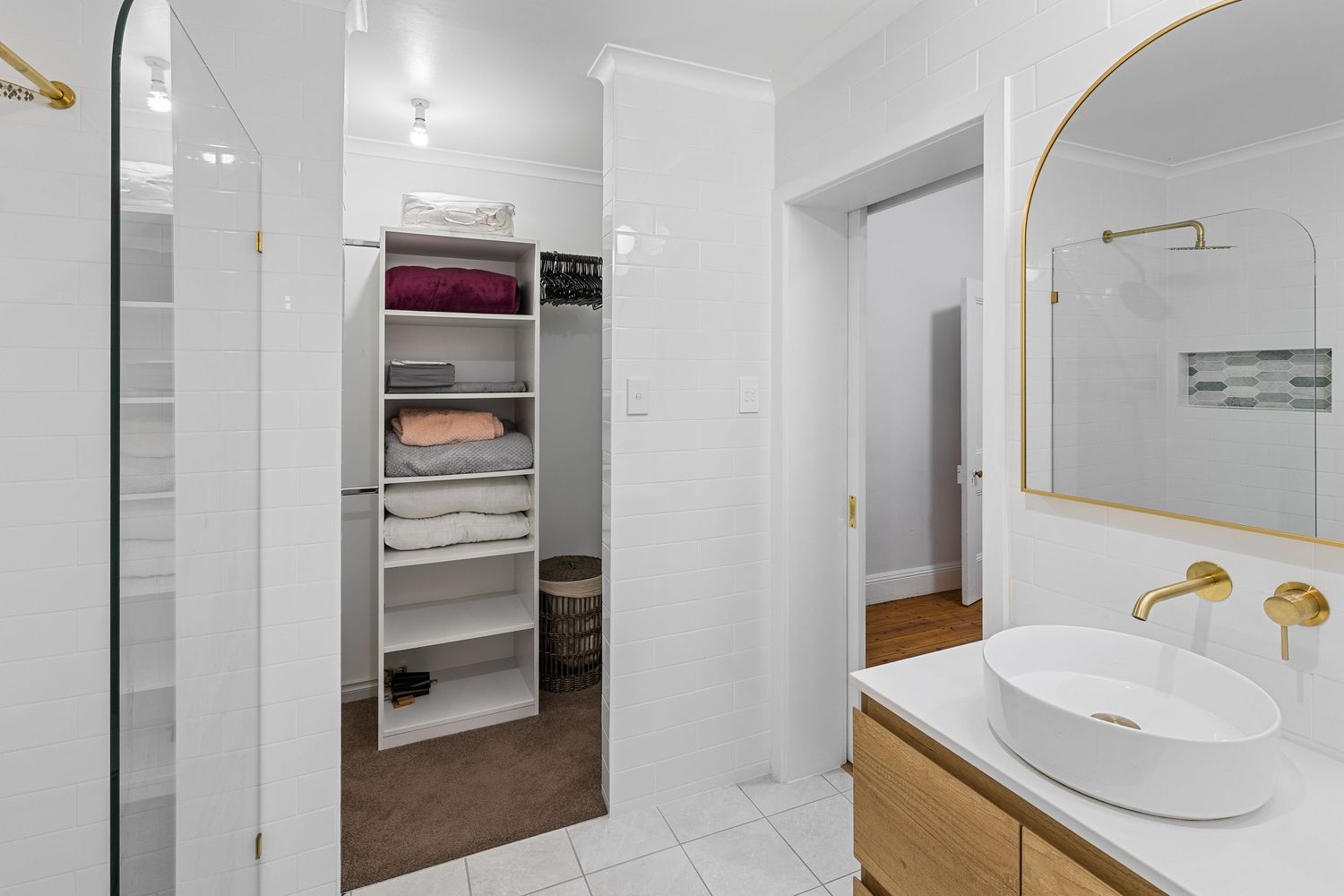 Modern white bathroom with freestanding tub, round mirror, and gold accents features clean lines and minimalist design.