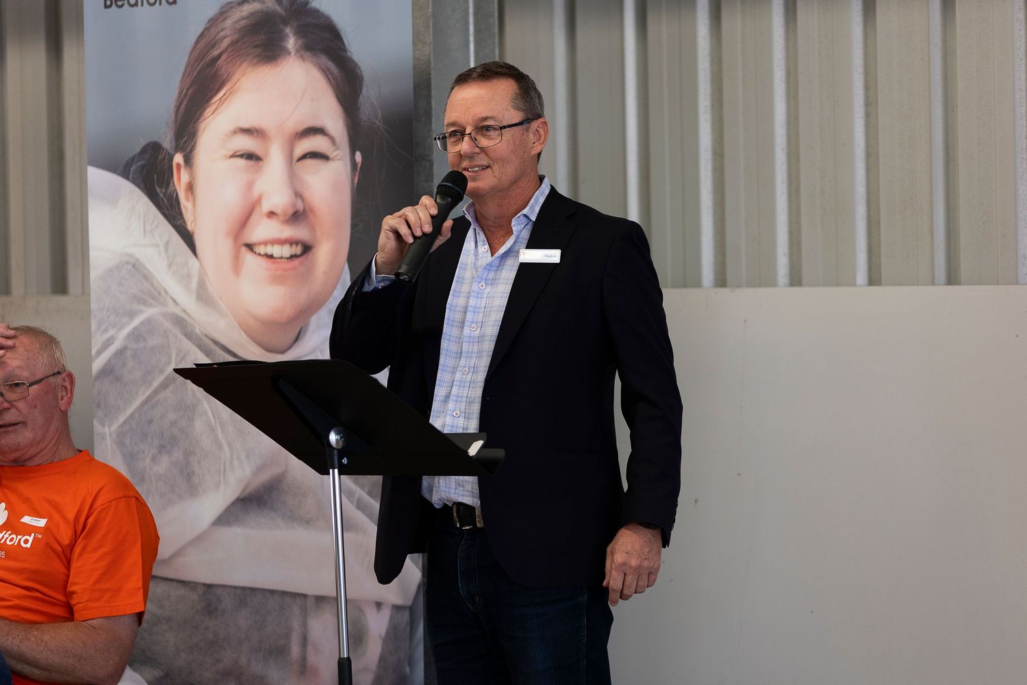 A speaker presenting at a podium during an indoor business event.