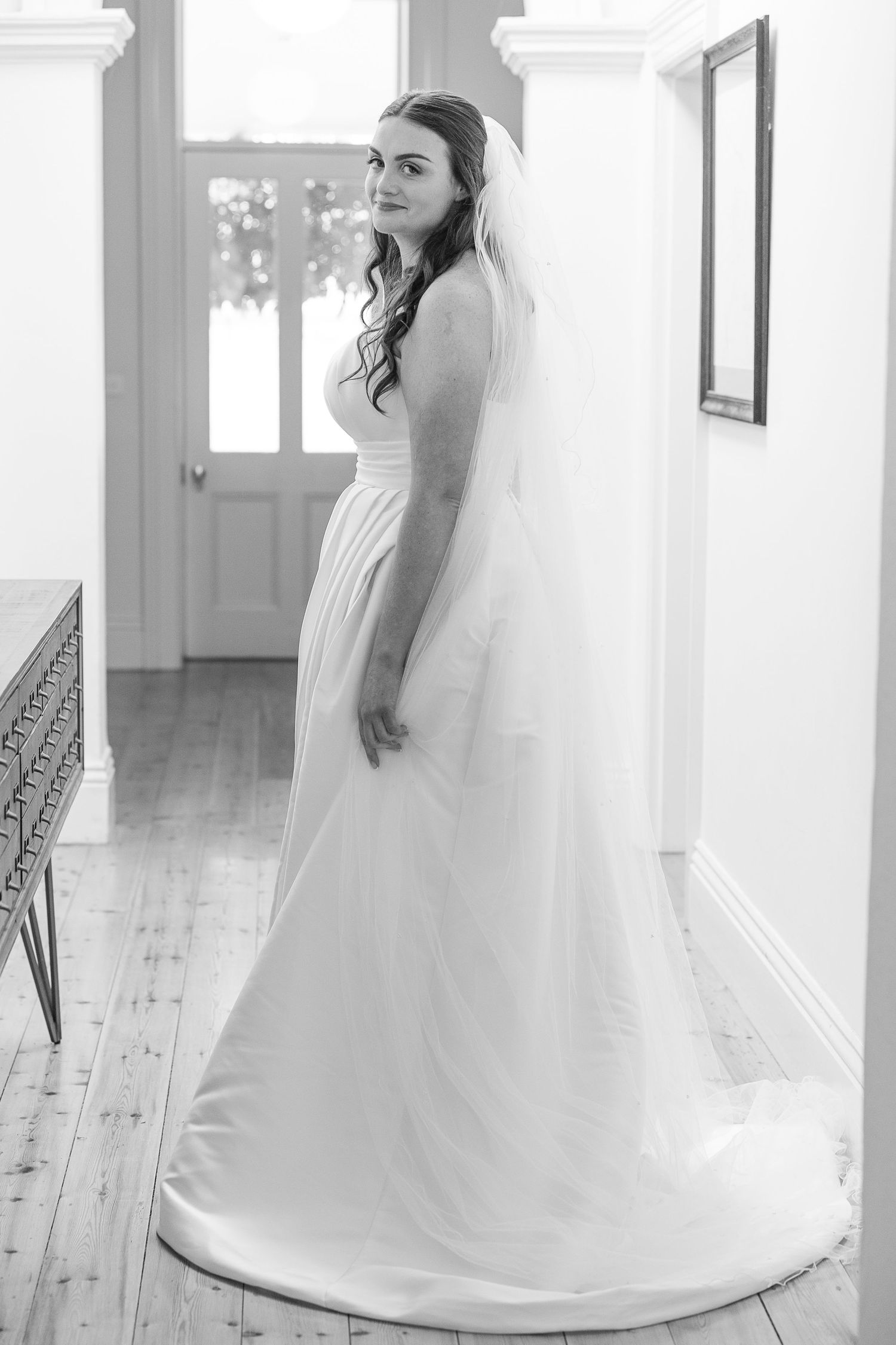 Ethereal bridal portraits in a bright white room showcasing a flowing wedding gown and veil.