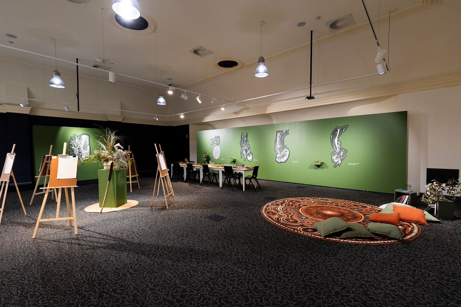 Art gallery interior with spotlit displays and green walls in a dimly lit space.