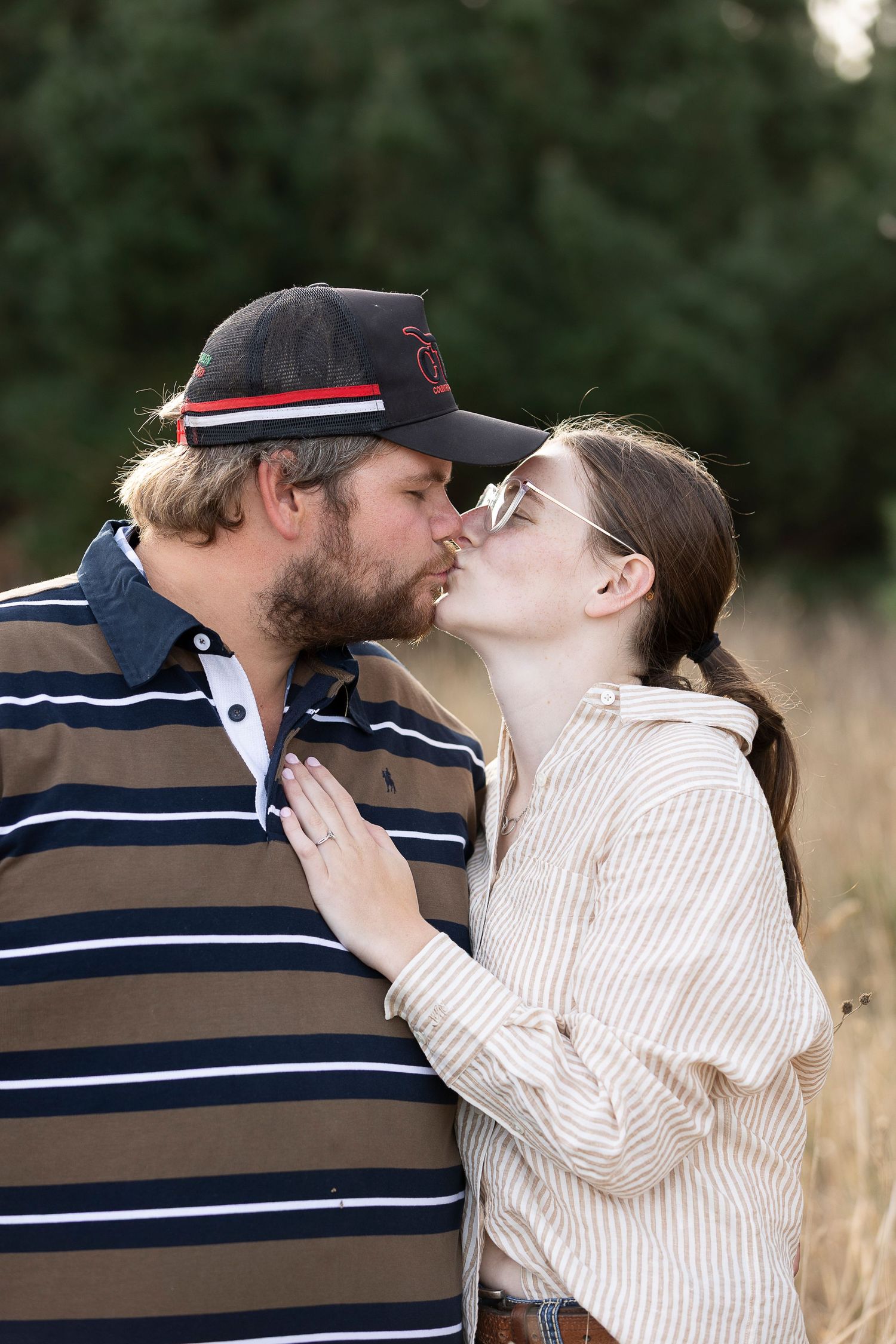 Couple shares tender moment in field during engagement photoshoot.