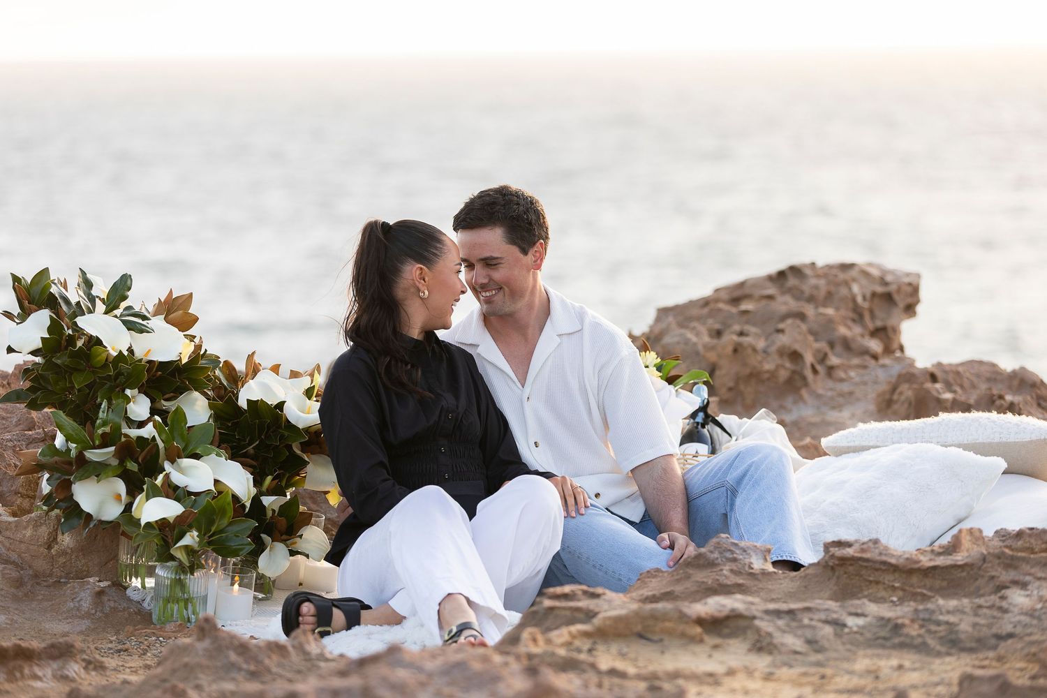Romantic couple enjoying a picnic on the beach at sunset.