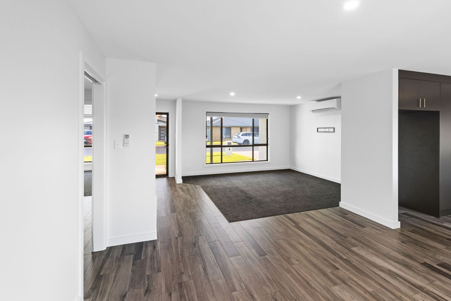 Contemporary open concept living area with dark hardwood floors and large windows providing natural light.