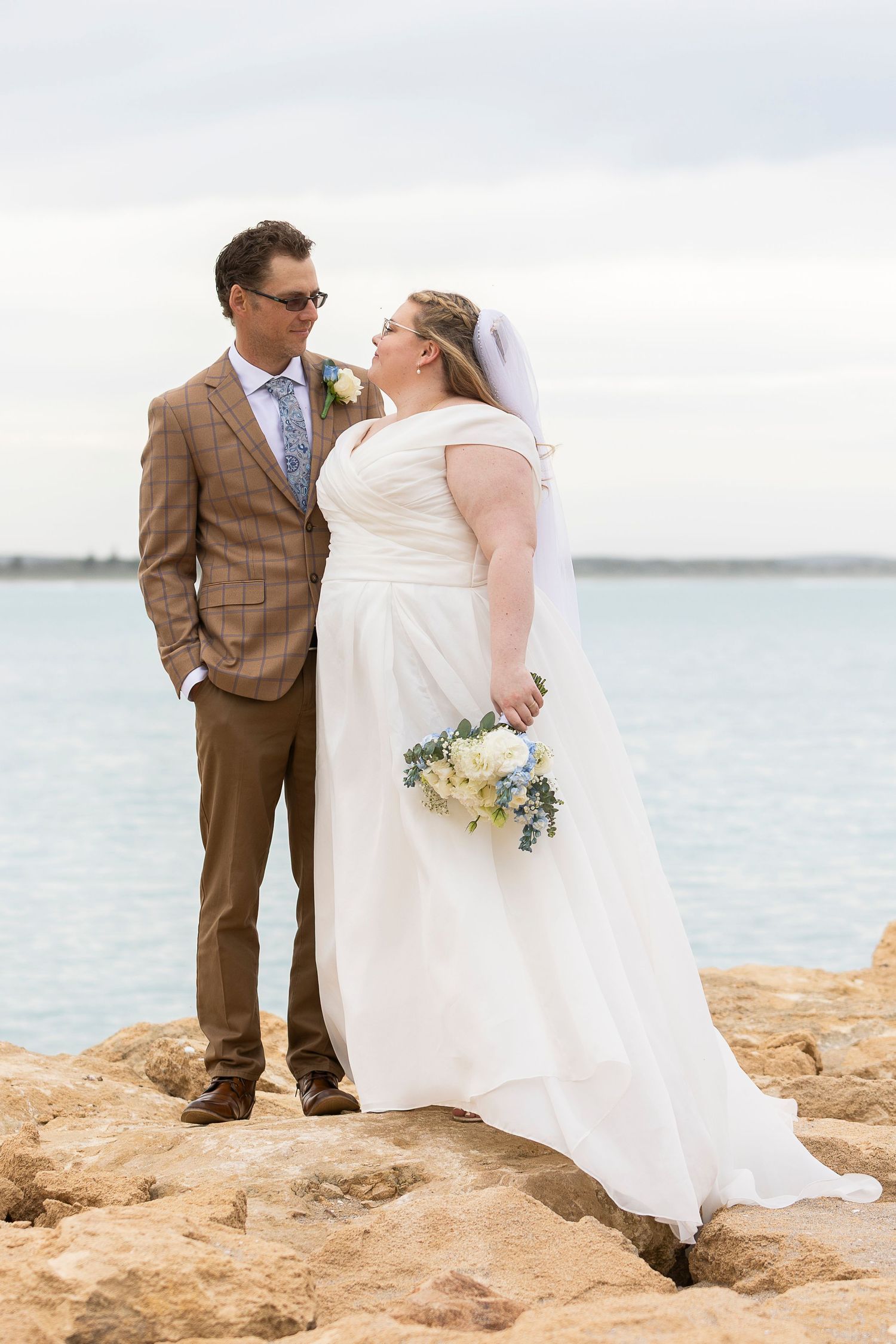 Wedding photo sequence of couple posing on rocky beach overlook.