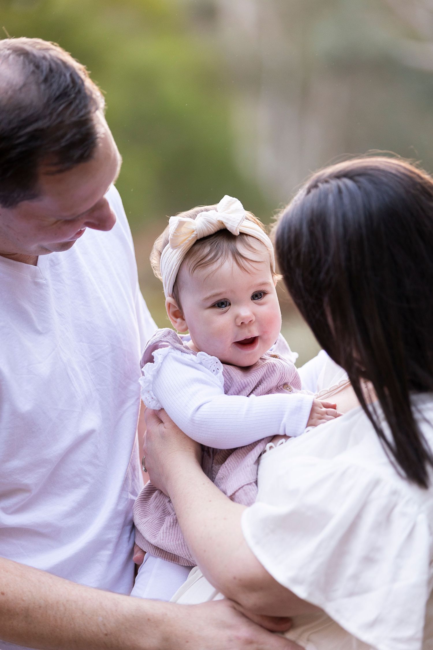 A series of tender moments between parent and baby in white clothing against a blurred background.