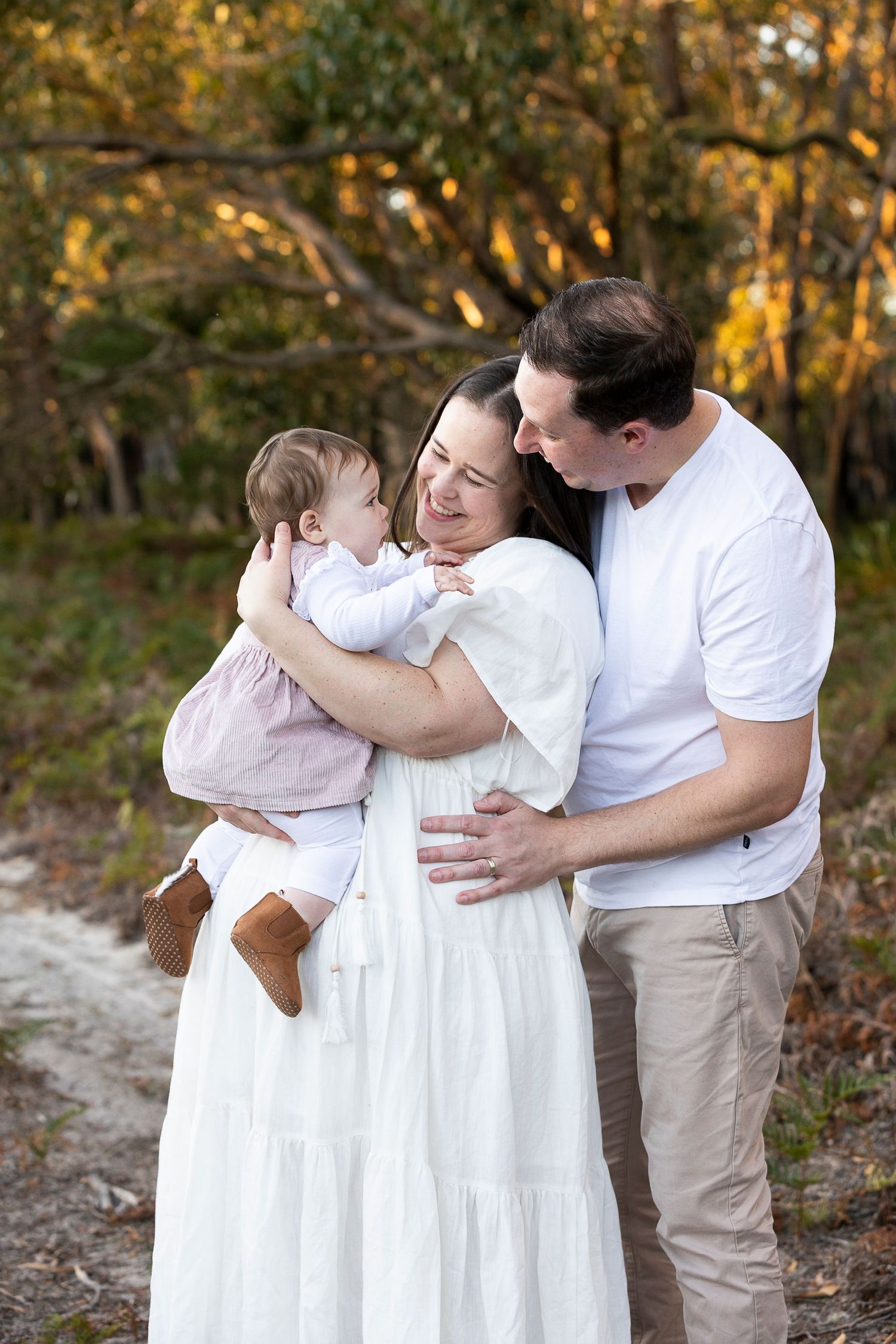 A family sharing an intimate moment together outdoors in white clothing.