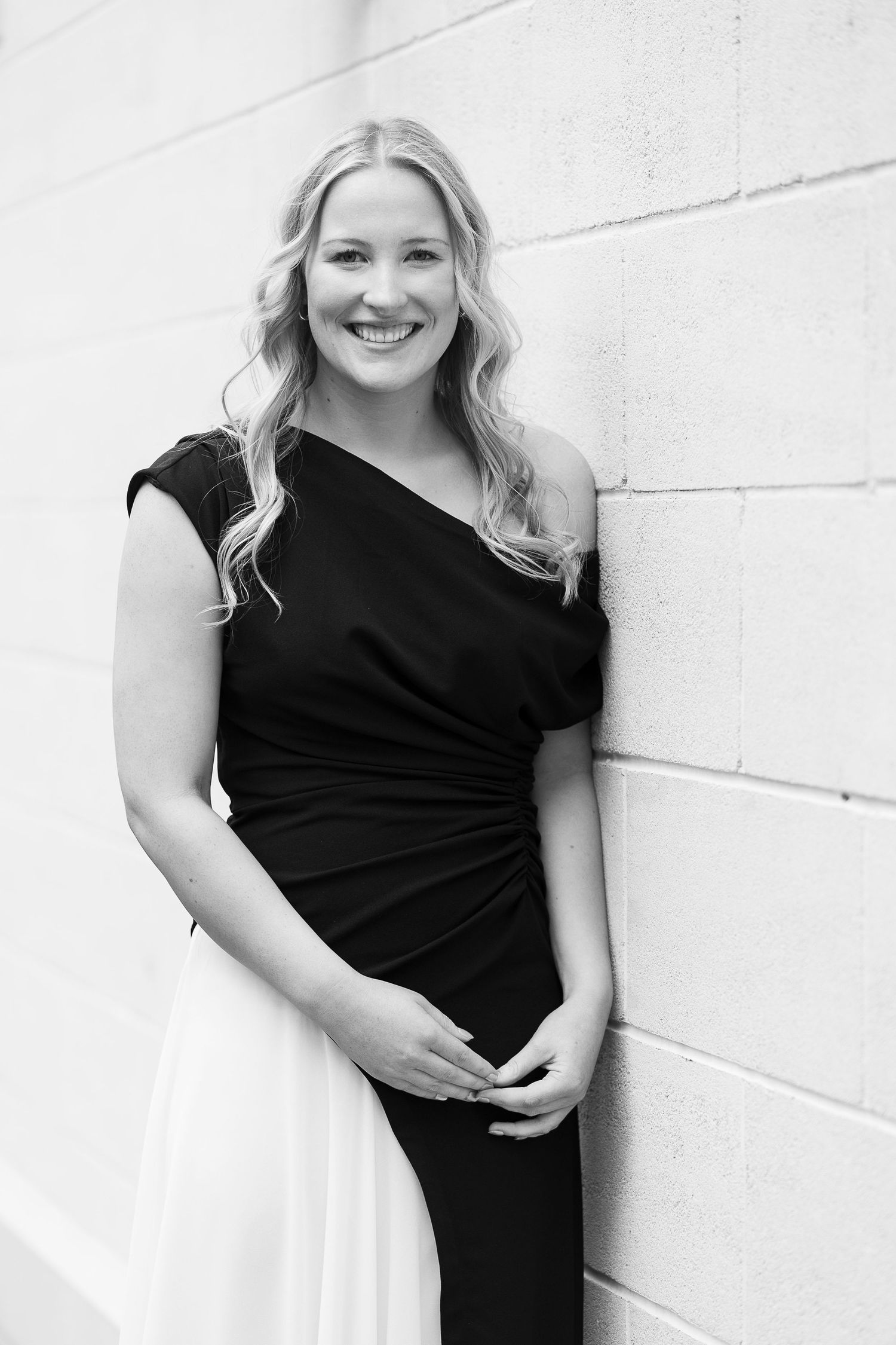 Black and white portraits showing someone in a two-tone dress against a white wall.
