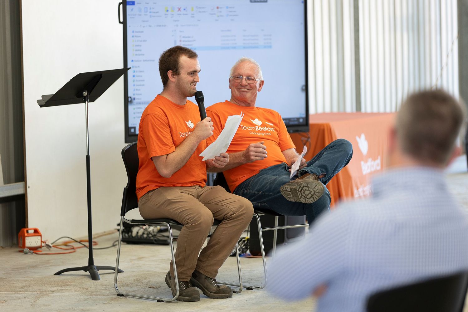 Group discussion taking place in a bright office space with orange-clad participants.