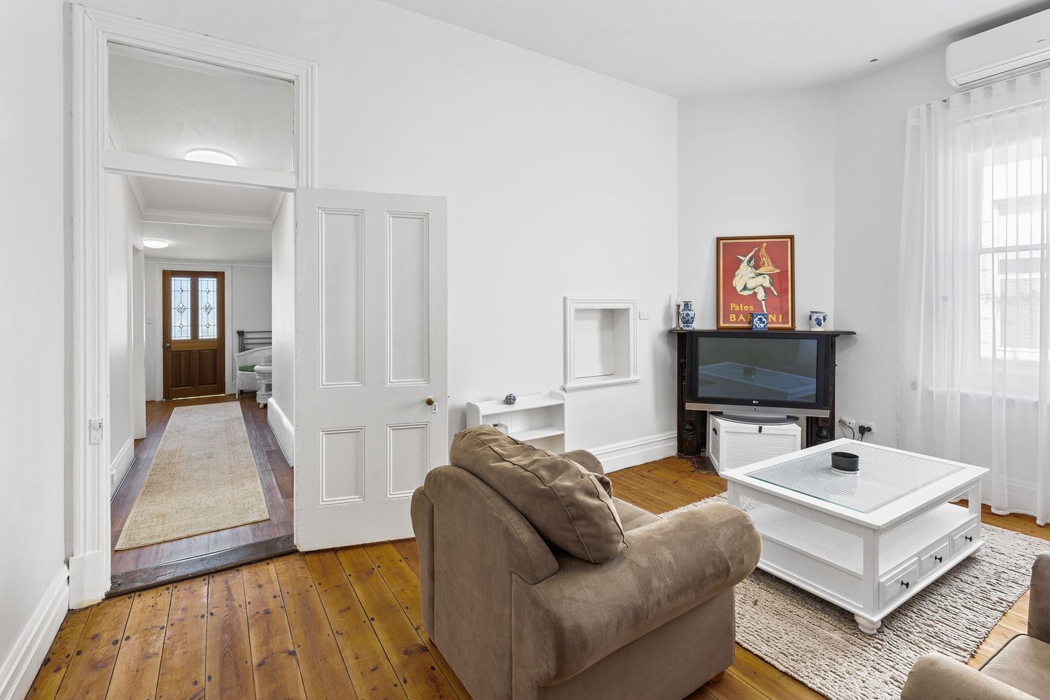 Bright white living space with hardwood floors and brown sofa showcases contemporary minimalist interior design.