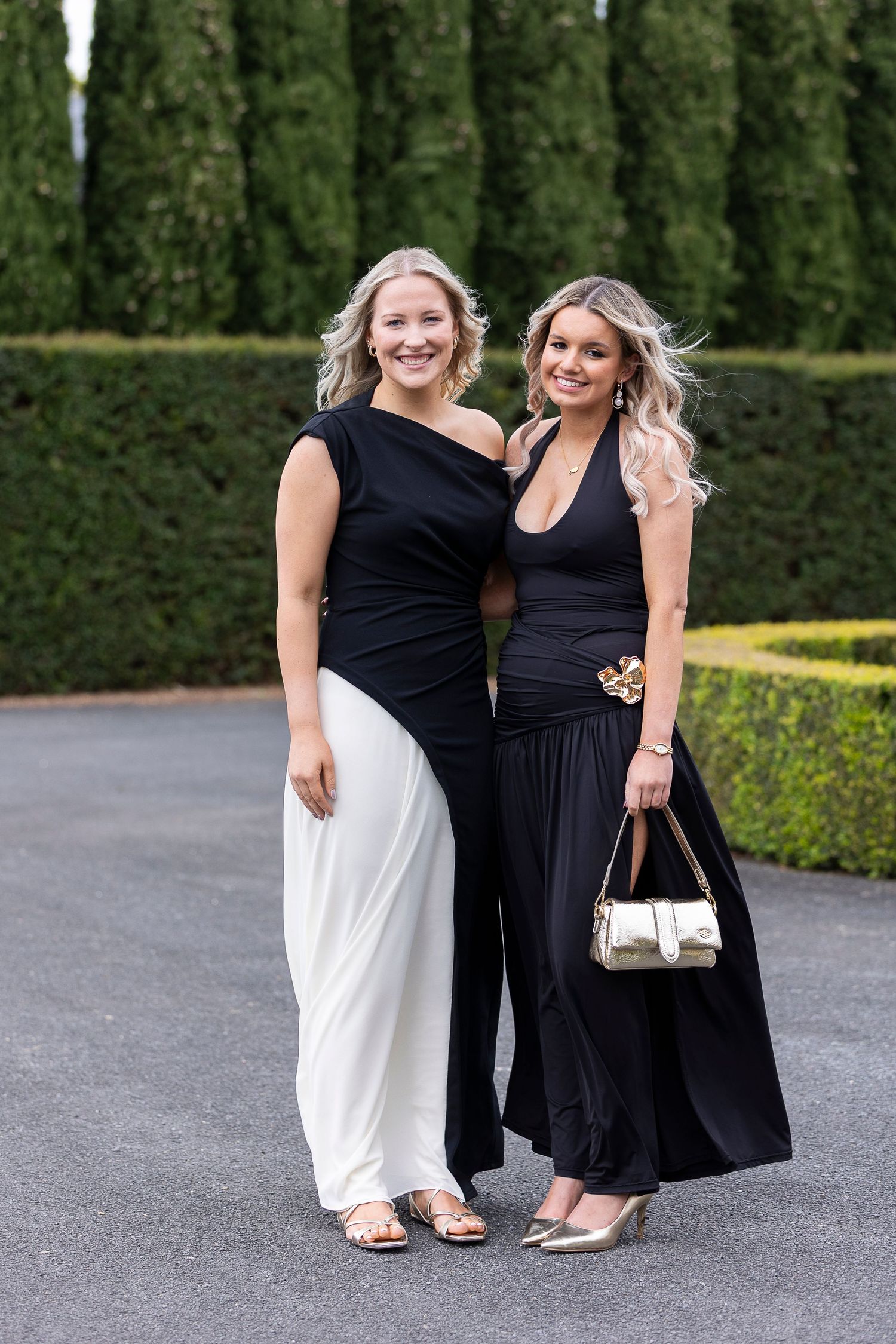 Two formal dresses shown in black and white against garden setting.