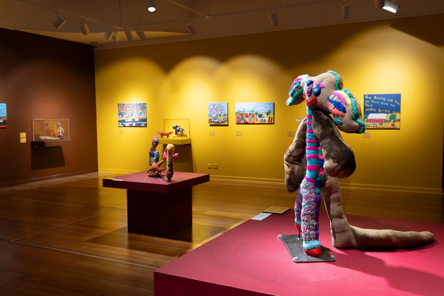 Art gallery interior with yellow walls displaying framed photographs and artwork.