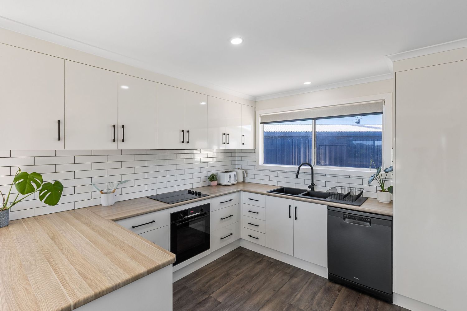 Modern white kitchen with wooden countertops, subway tile backsplash and stainless steel appliances.