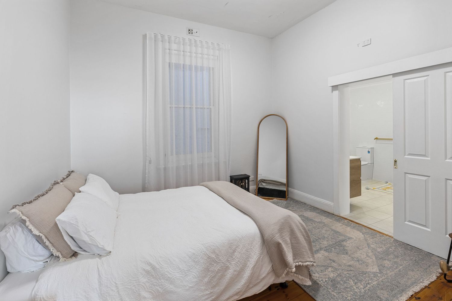 Clean white bedroom with vertical blinds and natural lighting.