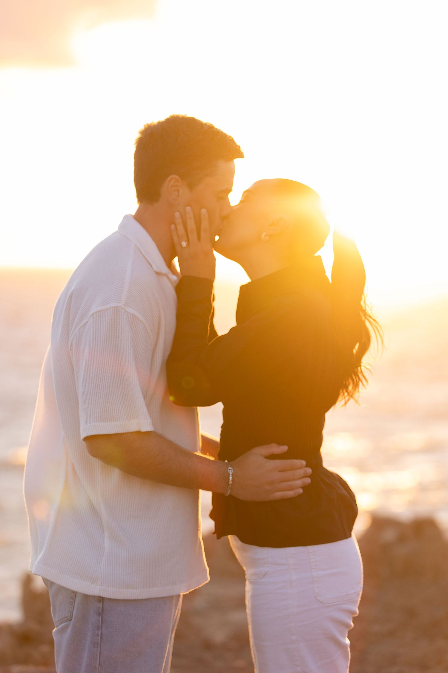 A couple shares an intimate moment silhouetted against a golden sunset.