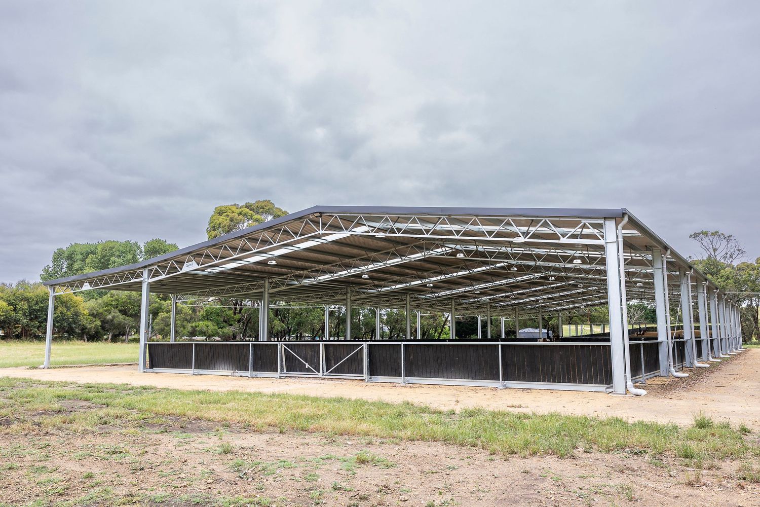 Panoramic view of a large covered equestrian facility with metal roofing.
