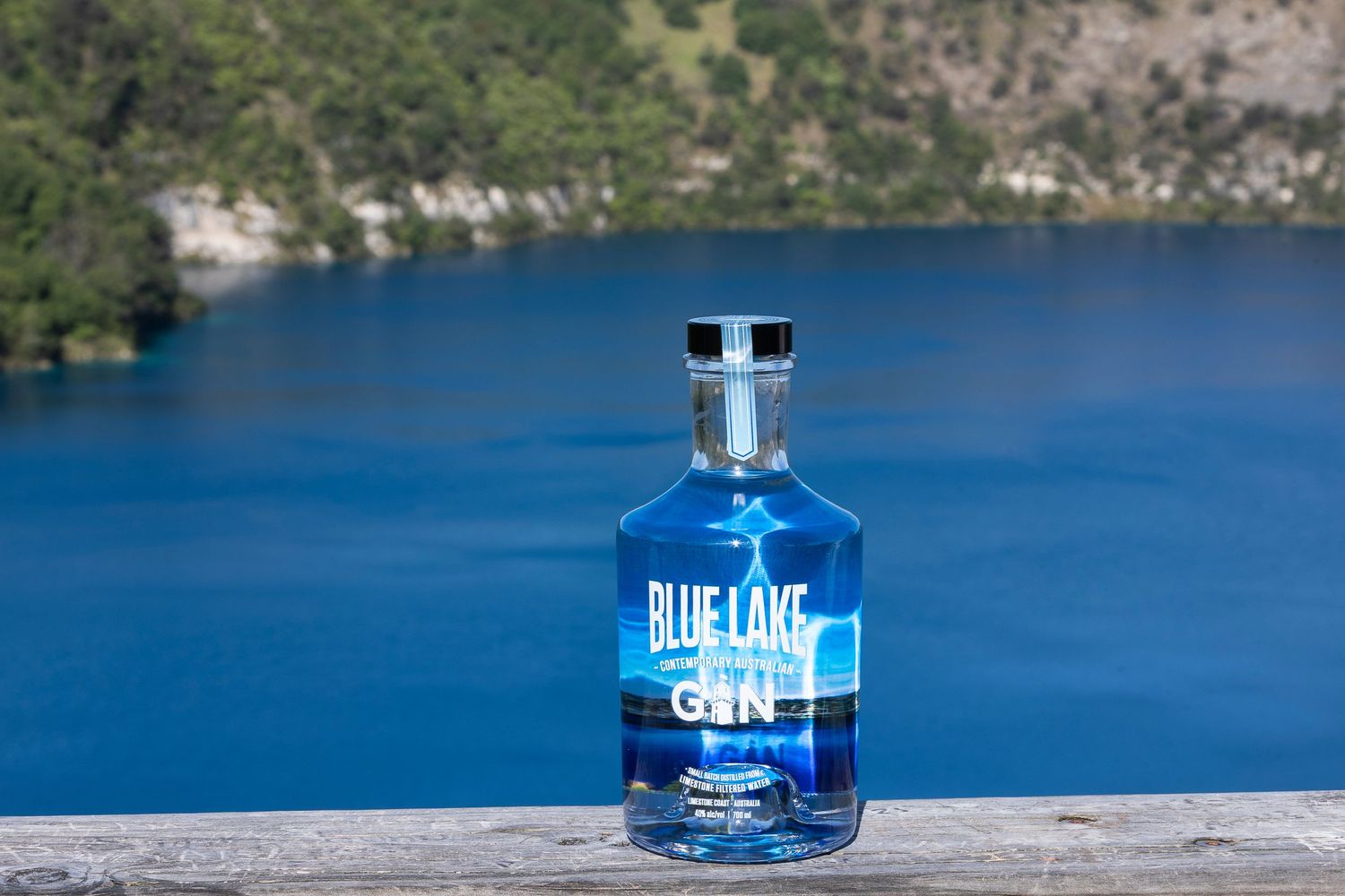 Blue Lake gin bottles arranged along waterfront with scenic lake views.