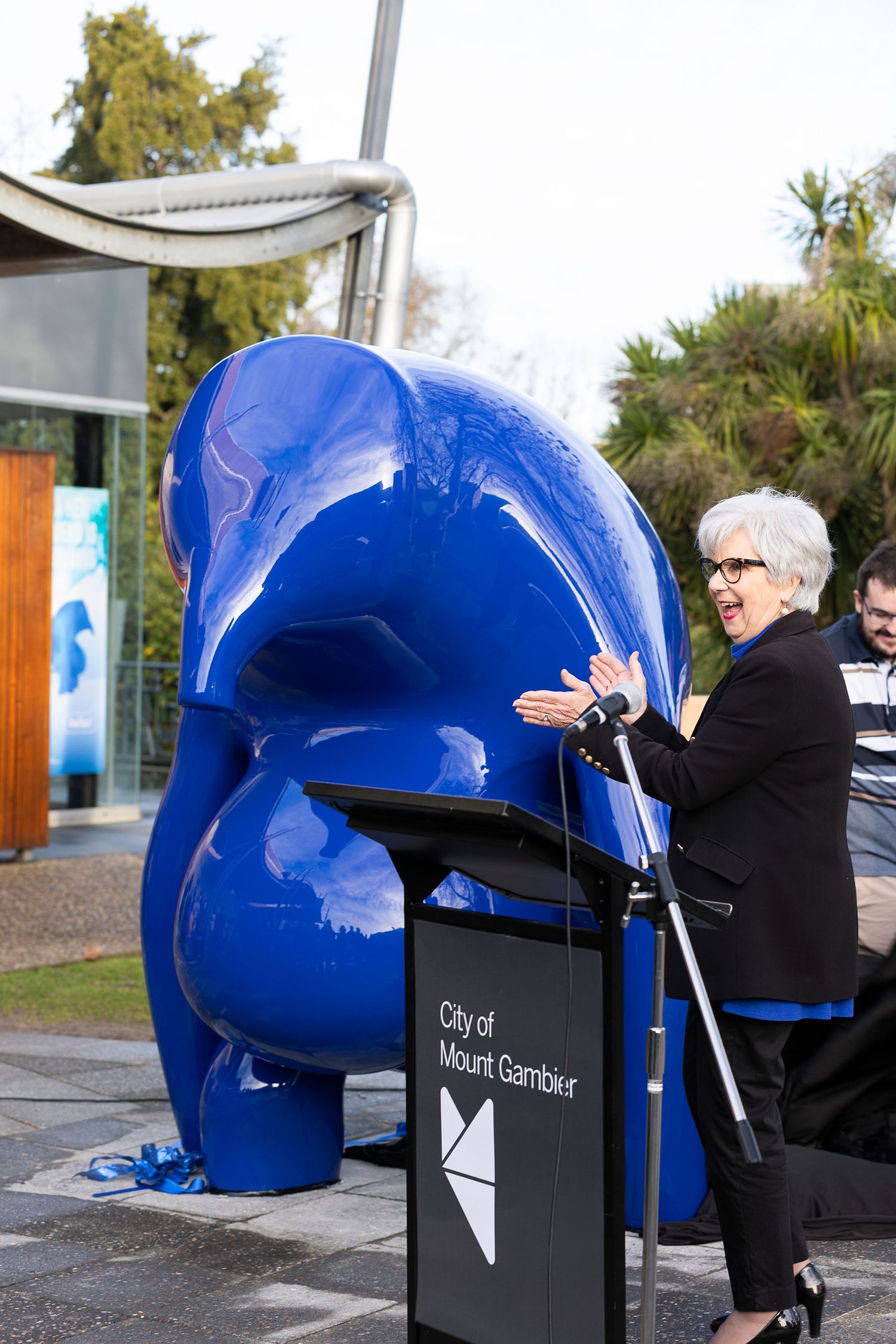 Large blue sculptural installation being unveiled outdoors.