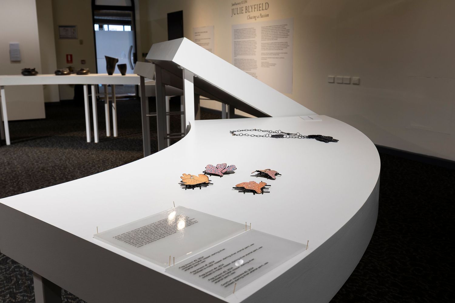Contemporary art installation featuring white curved display surfaces in a minimalist gallery setting.