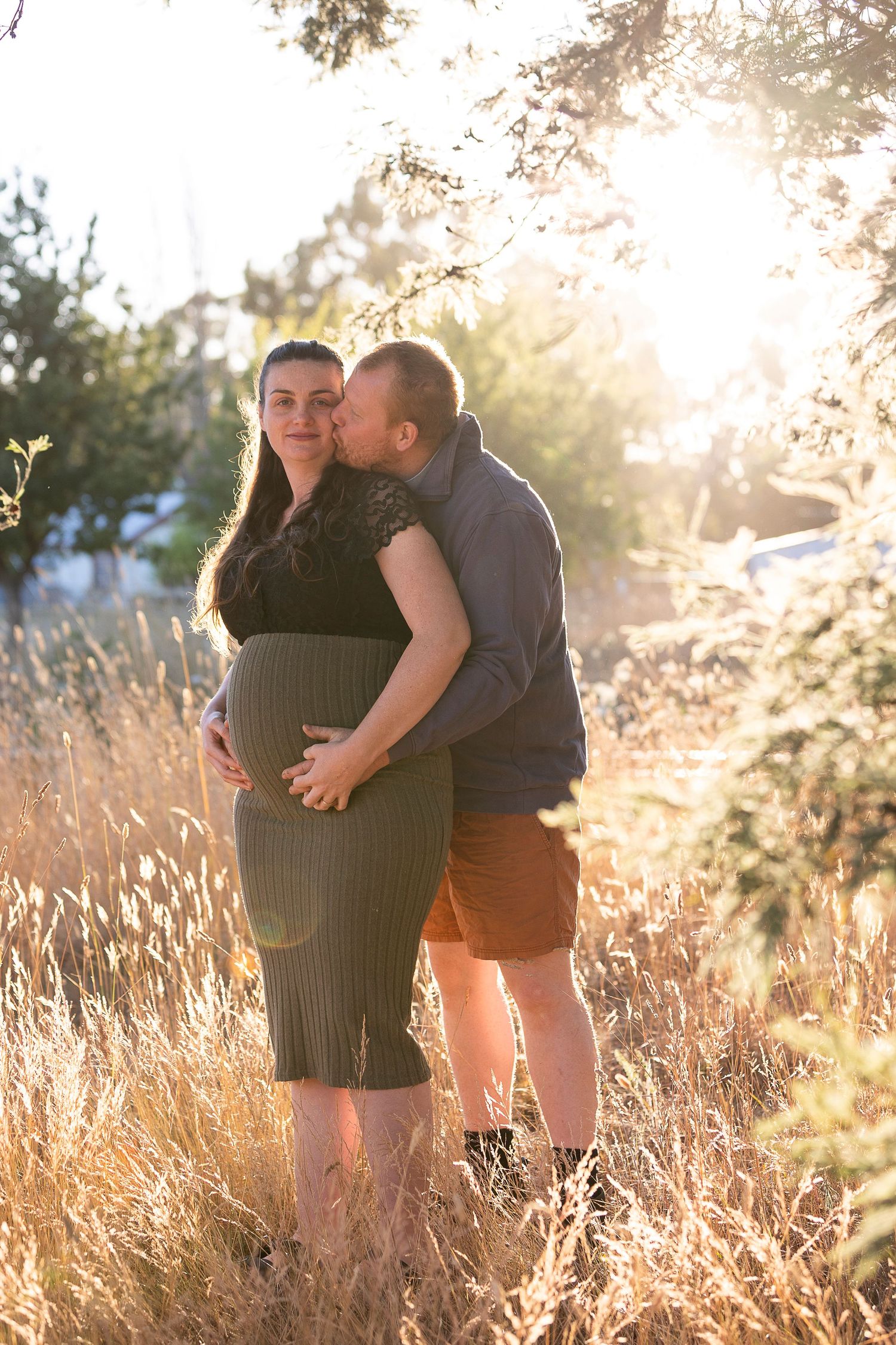 Romantic couple sharing intimate moment in golden field at sunset.