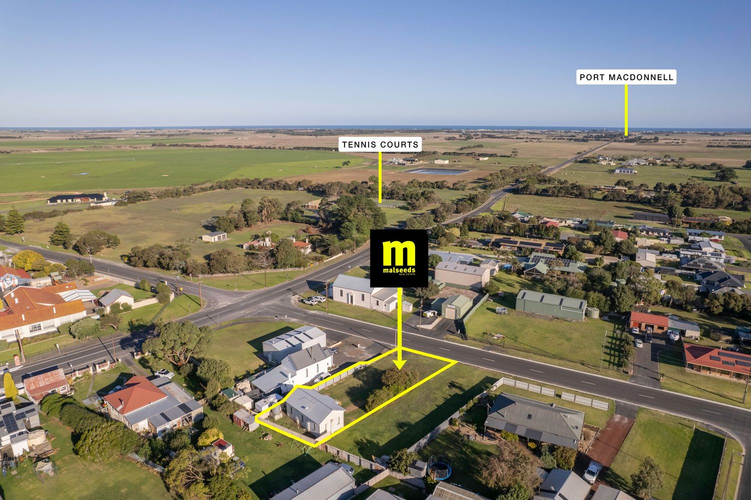 Aerial view of a residential property in Port MacDonnell, South Australia, with tennis courts and rural landscape visible.