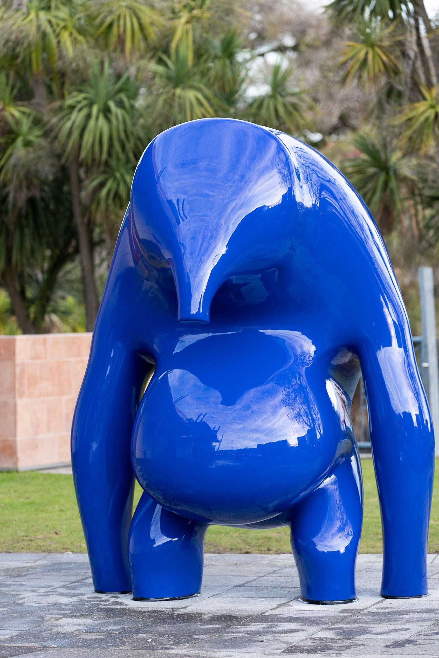 Bright blue elephant forms displayed in an outdoor setting with trees.