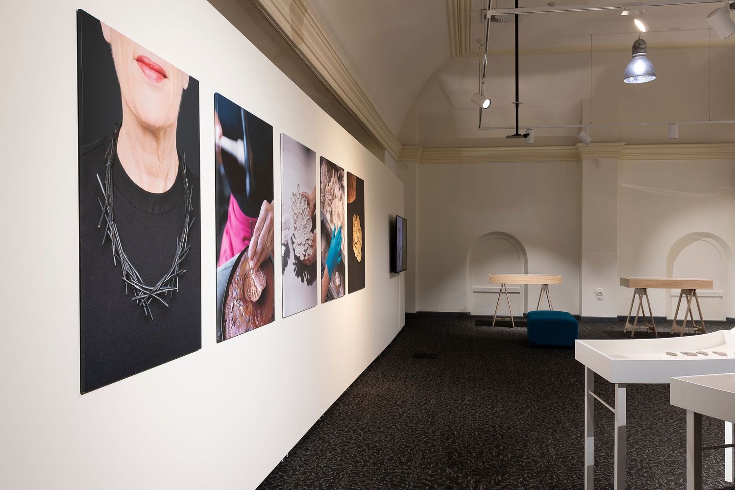 Modern gallery interior with white walls, track lighting, and curved exhibition furniture.