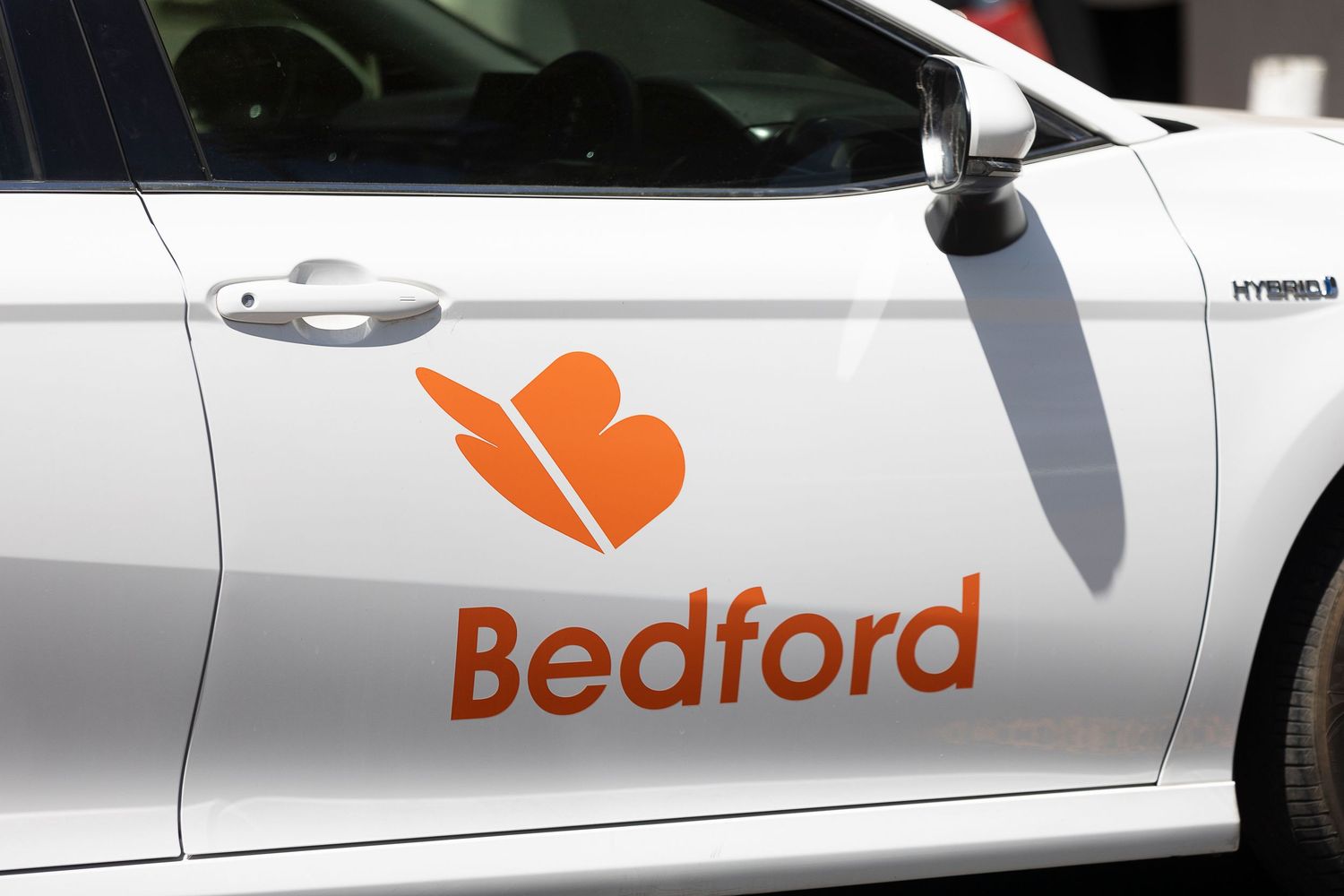 A fleet of white Bedford delivery vans with orange company logos parked in a row.