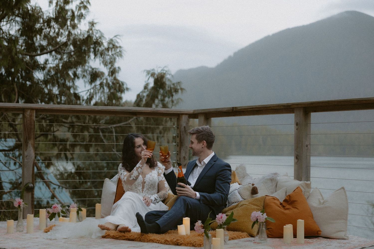 Tofino intimate wedding near Ucluelet outdoor dining setup with candles and cushions against a serene mountain backdrop
