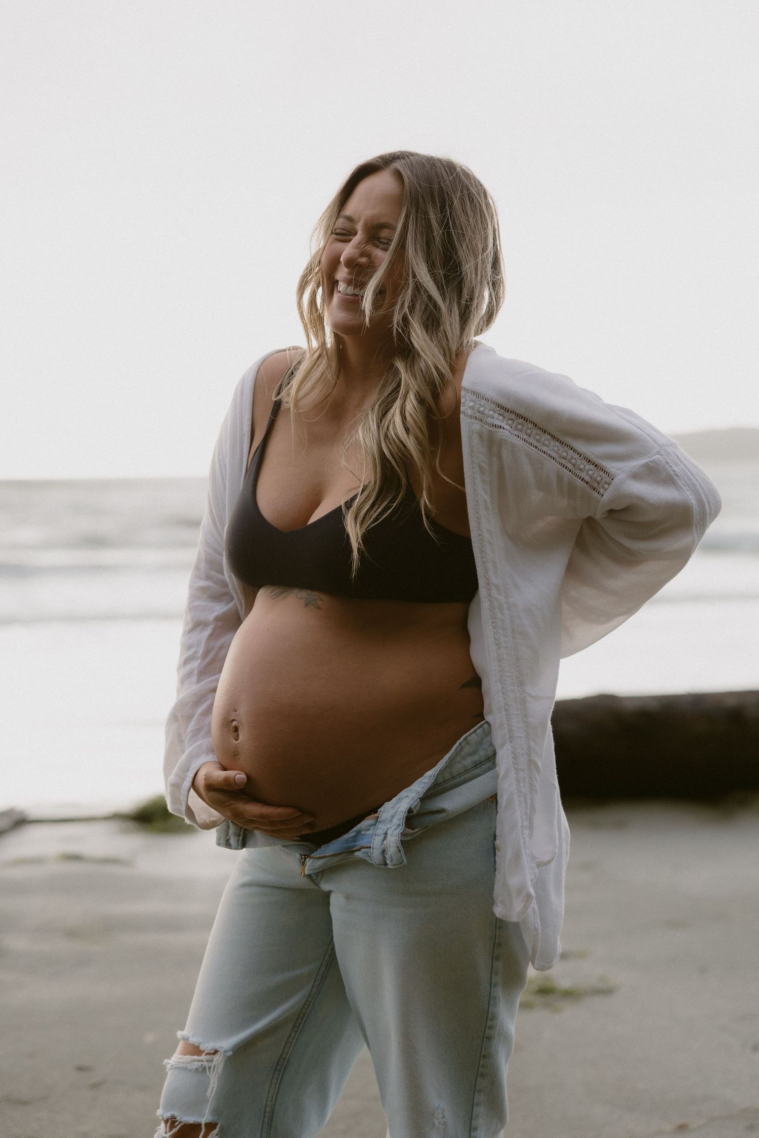 Casual beach maternity photos with white button-down shirt and light denim.