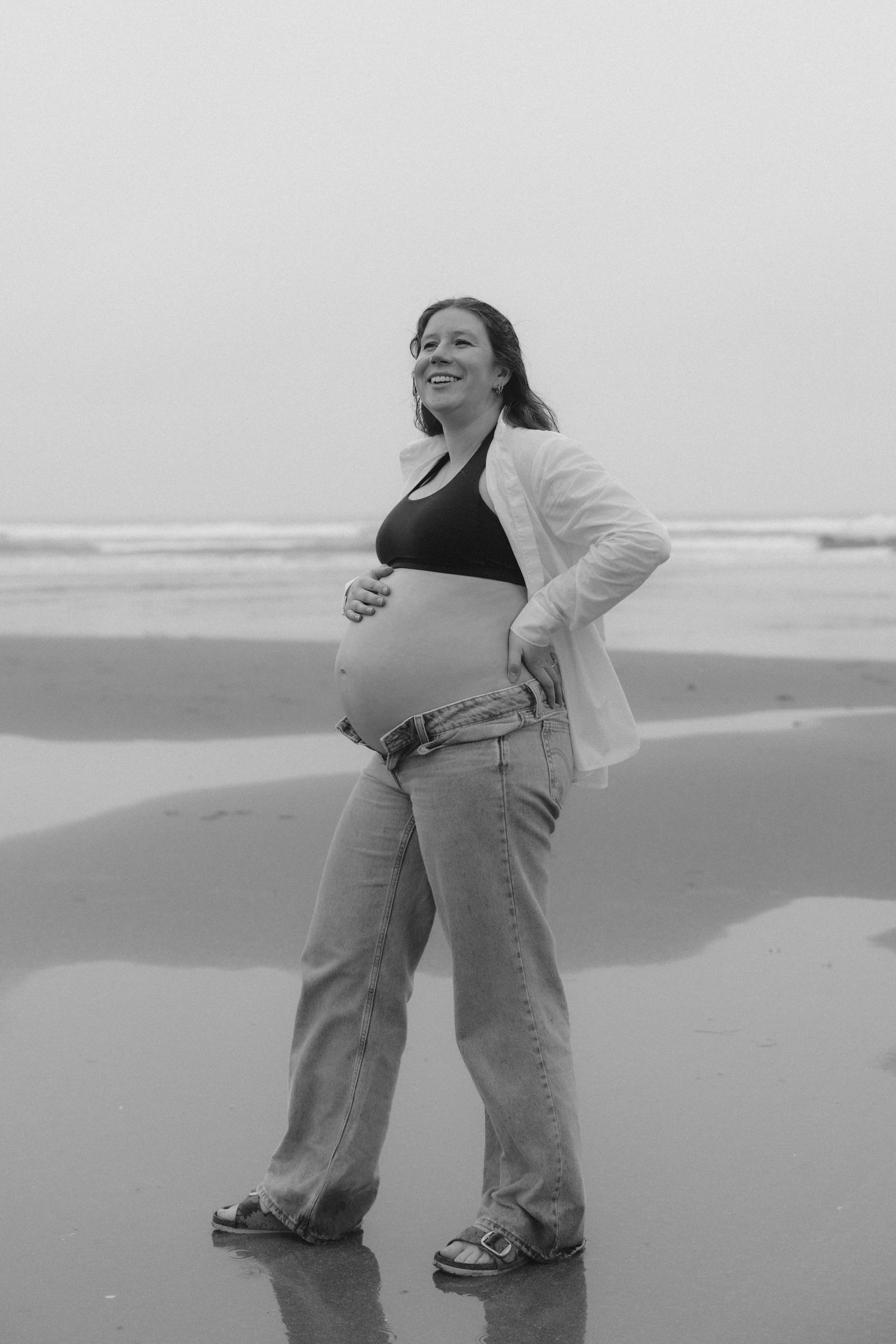 Playful couple dancing together on a misty beach in casual attire.