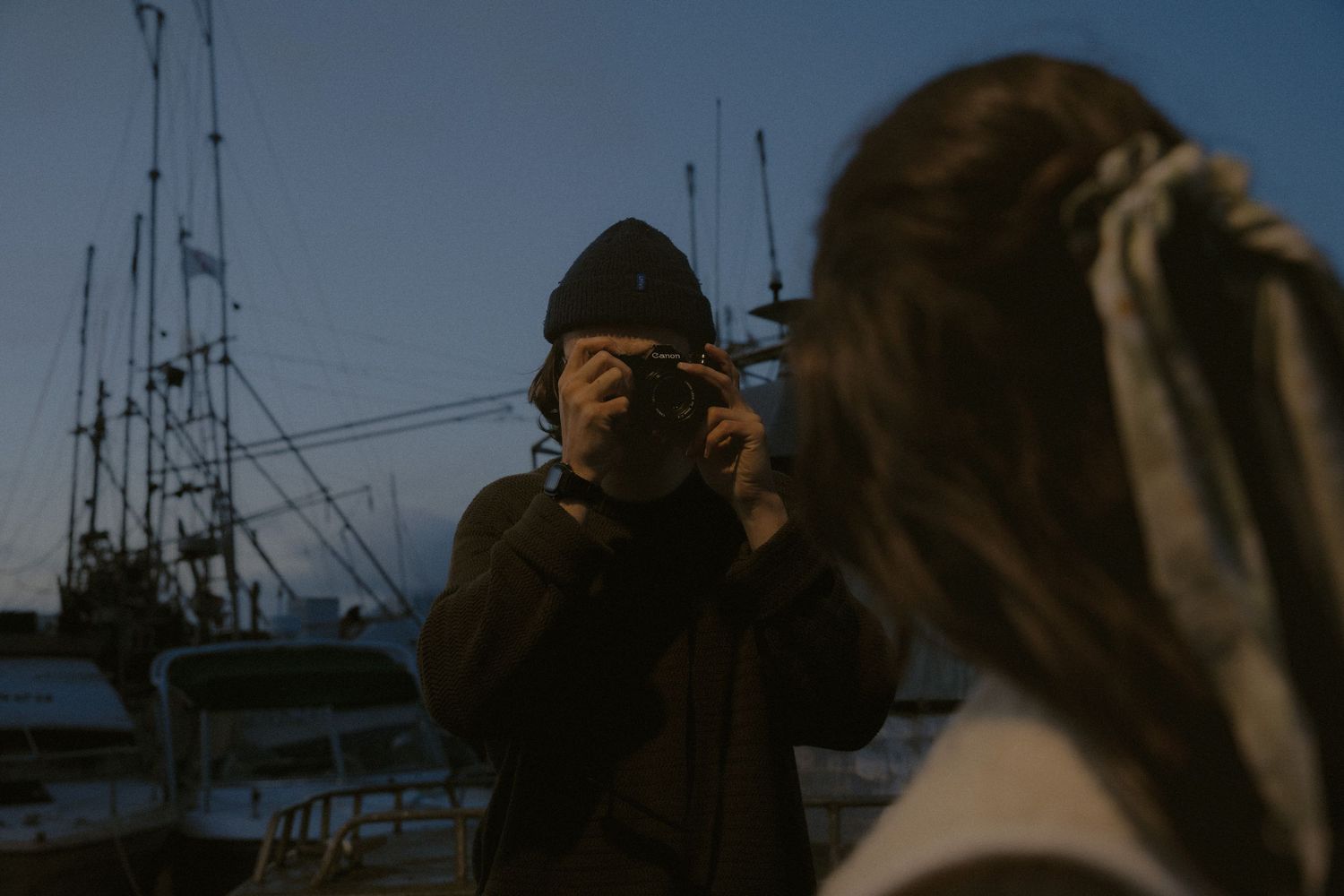 Dark silhouettes of people on a marina dock during blue hour.
