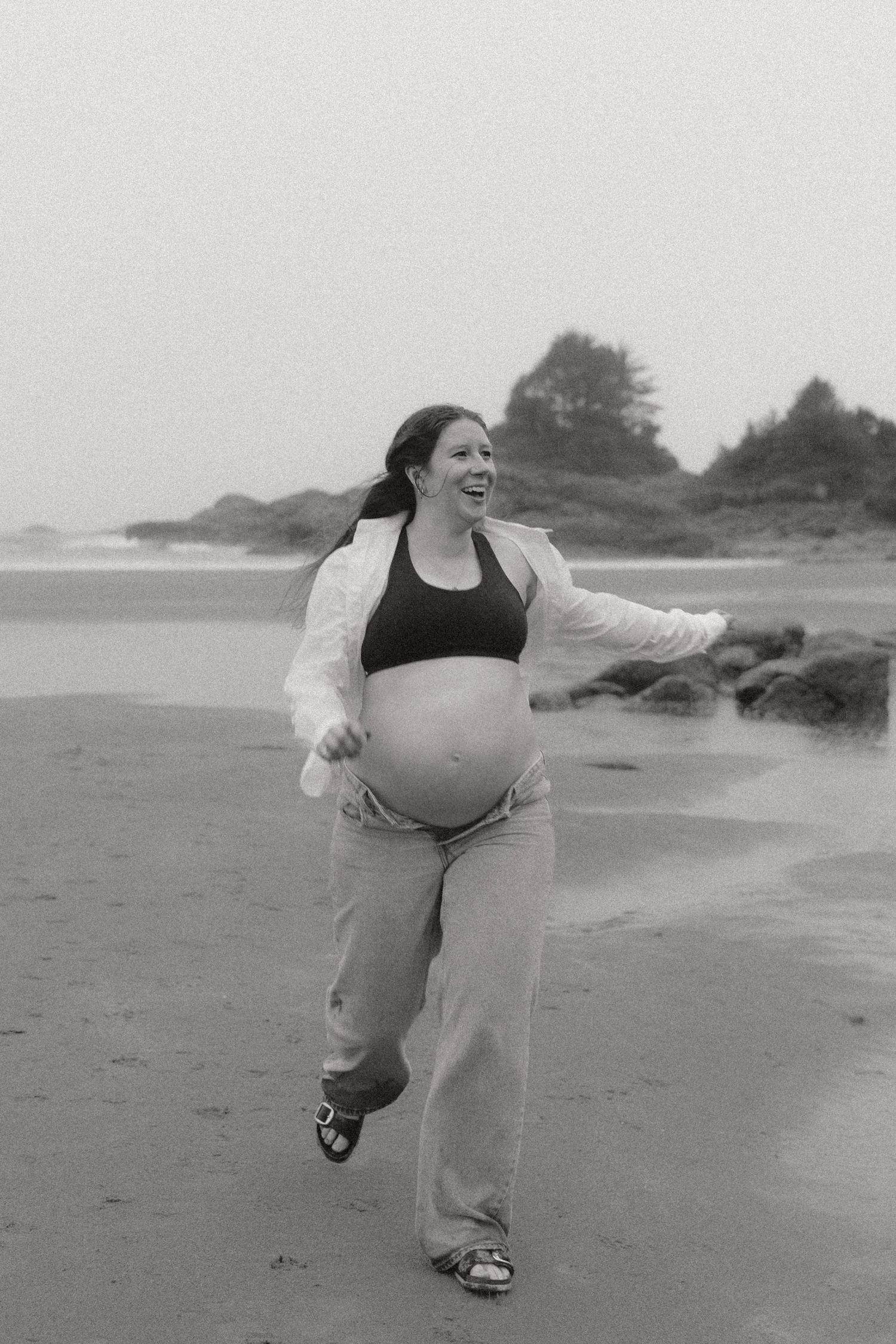 A joyful dance sequence captured on a misty beach in black and white.