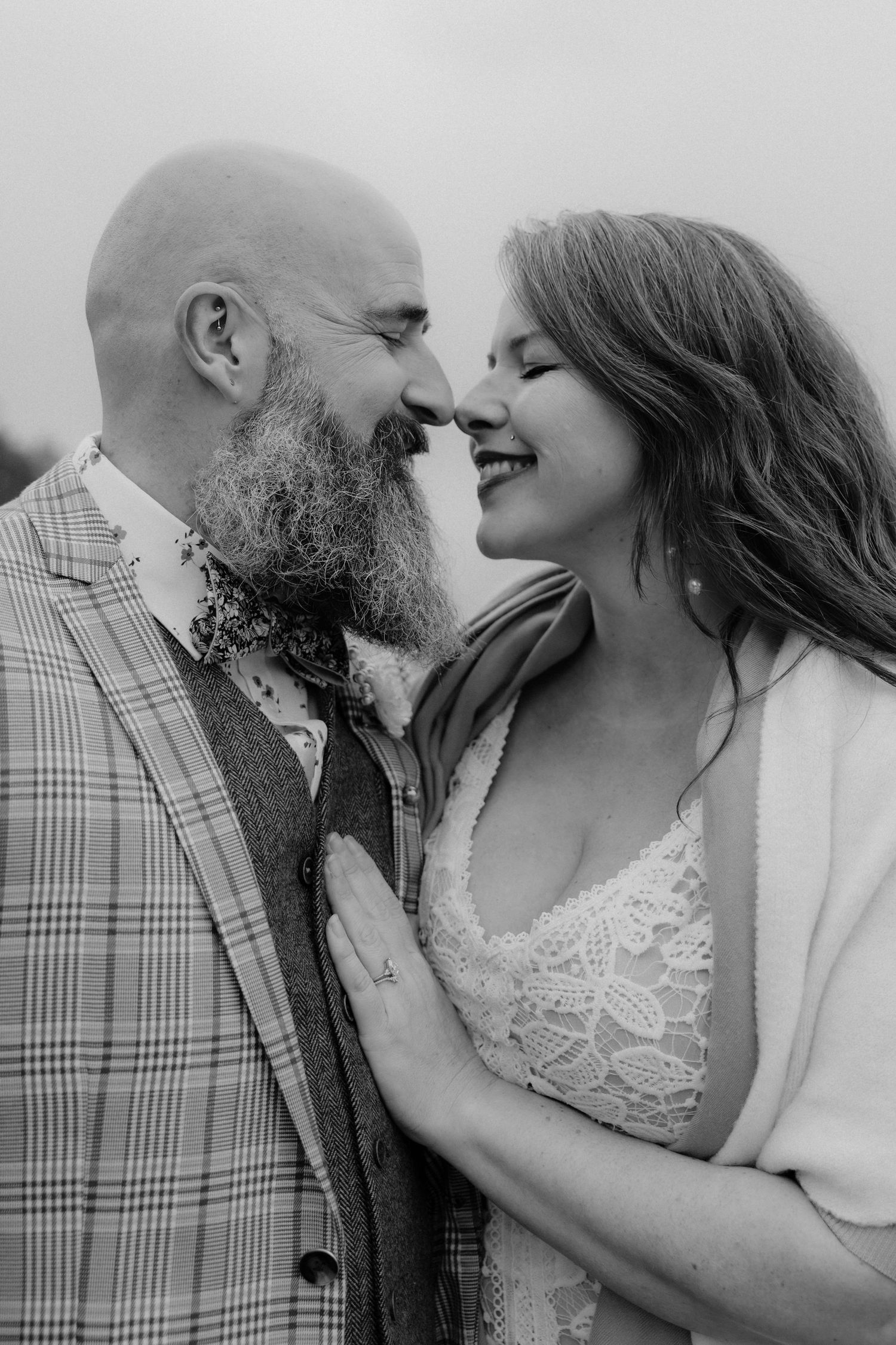 An intimate black and white portrait of a couple laughing together on the beach.