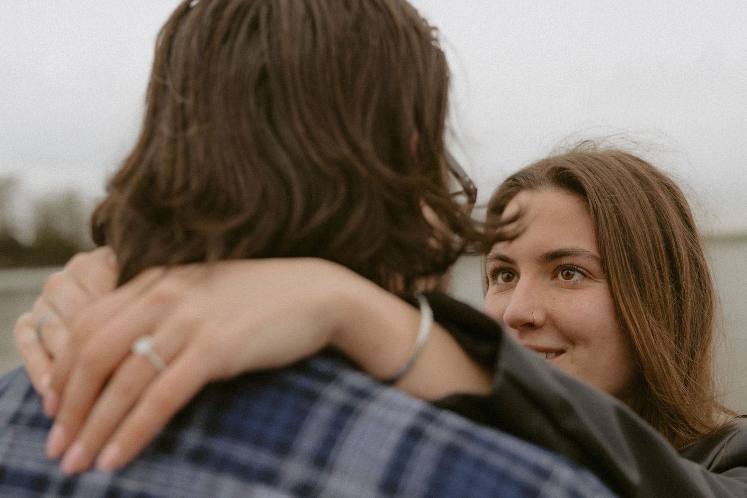 Tofino engagement intimate embrace showing hands with engagement ring against cloudy beach backdrop