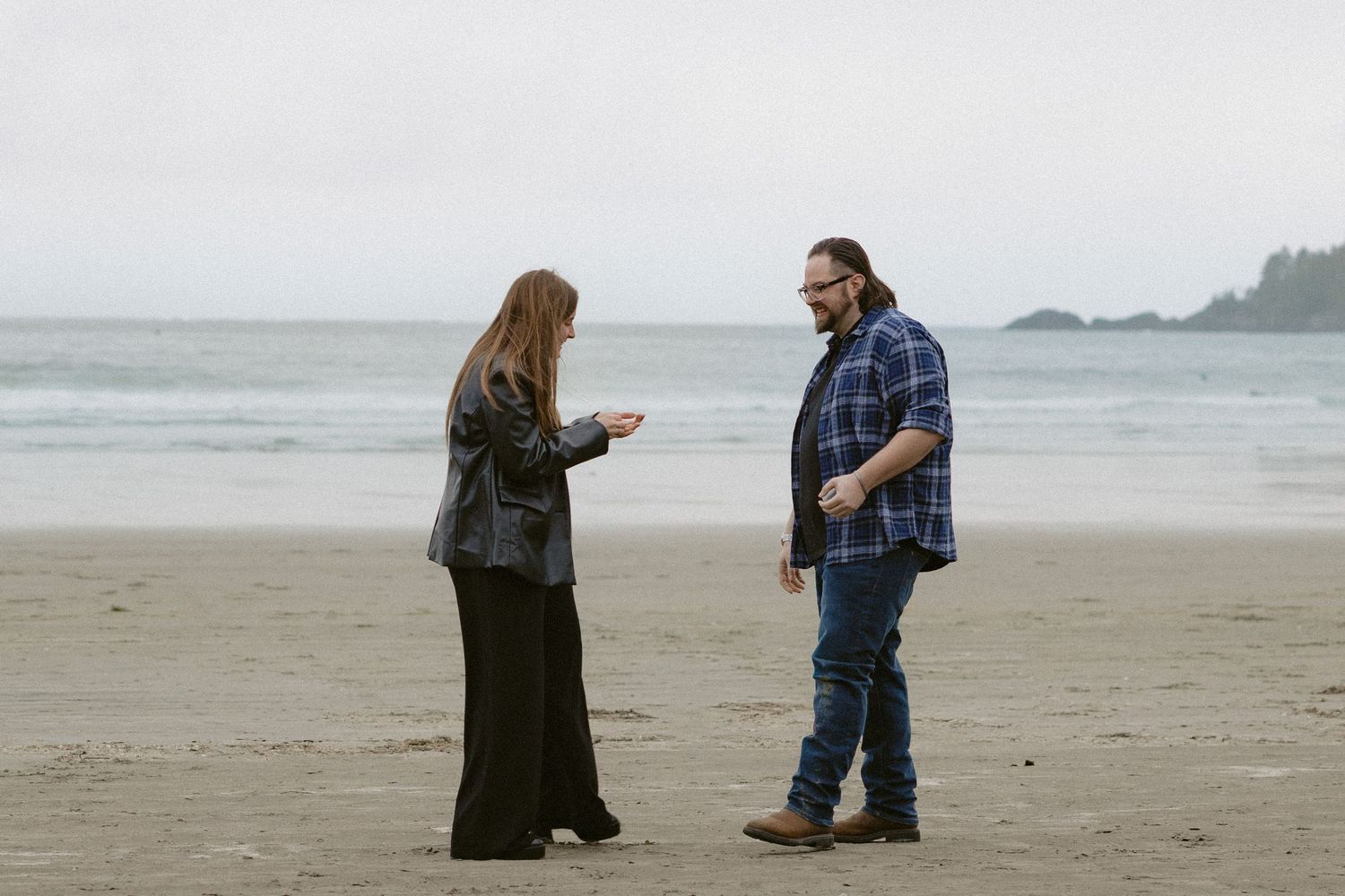 A couple shares a tender moment on a misty Pacific Northwest beach.